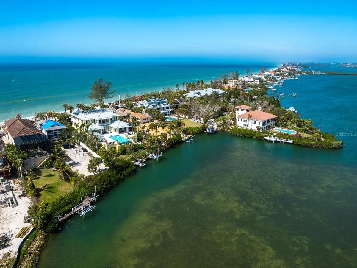 Sarasota Motor Club - Exotic Car Consignment Sarasota - Aerial view of waterfront houses and condos along a canal with the ocean in the background.