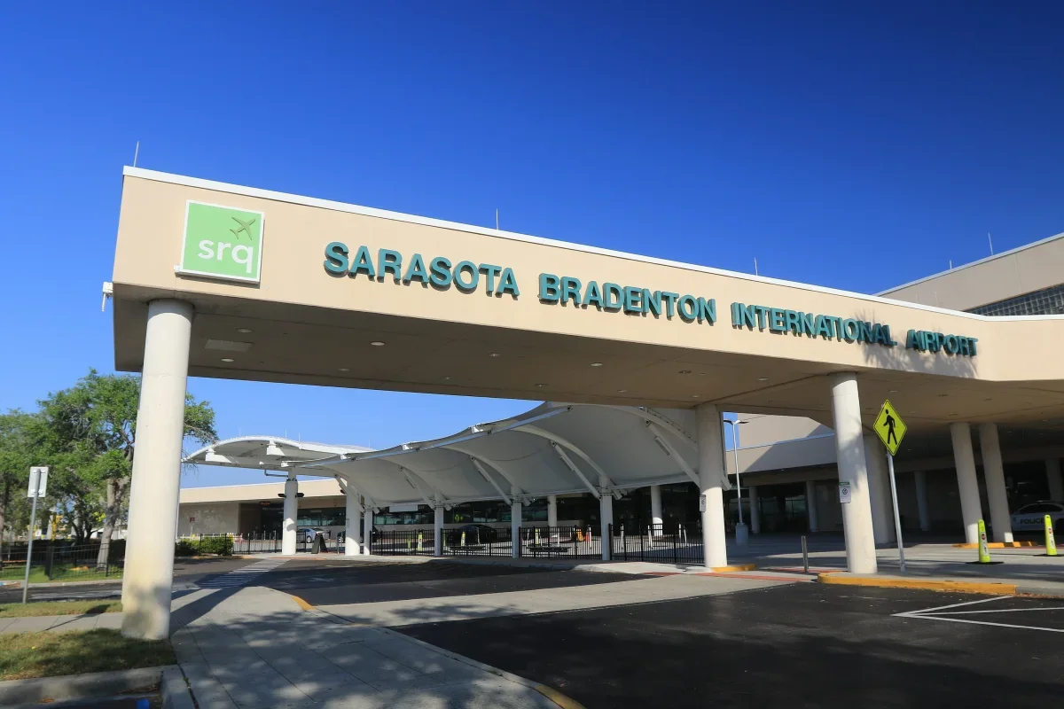 Sarasota Motor Club - Luxury Car Sarasota -Entrance to Sarasota Bradenton International Airport with a sign displaying the airport's name and the SRQ logo.