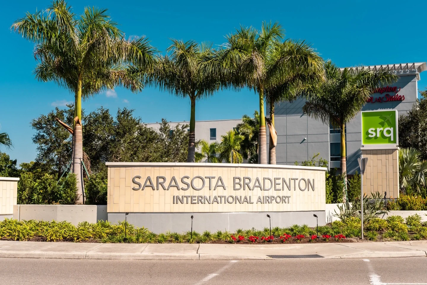 Sarasota Motor Club - Luxury Car Sarasota - Sign at Sarasota Bradenton International Airport with palm trees and hotel in the background.
