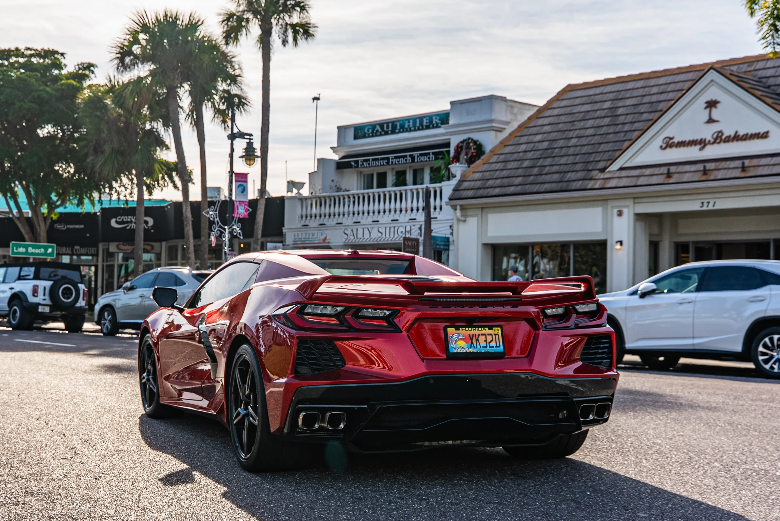 Sarasota Motor Club - Lido Key & St. Armands Circle exotic car rental - Red Corvette parked on a street with storefronts and palm trees in the background.