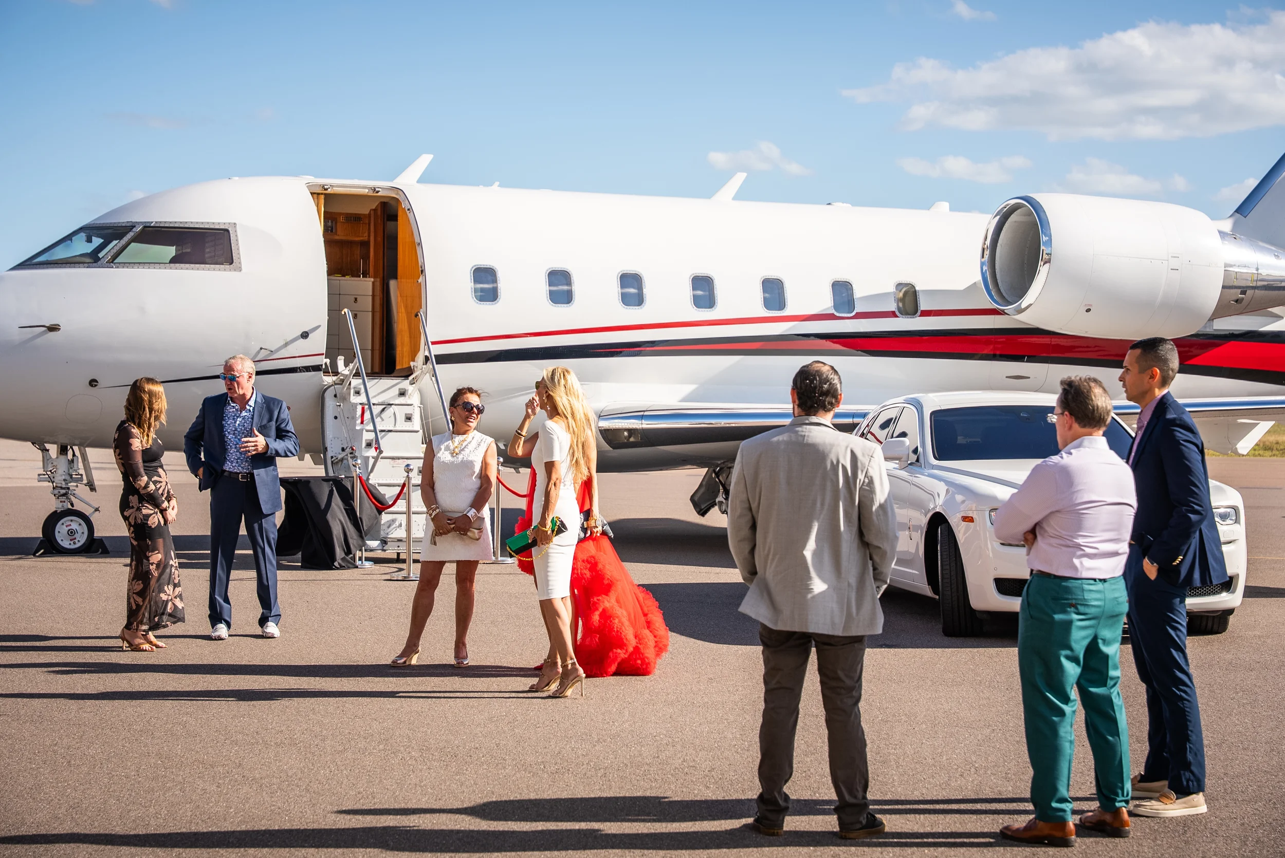 Business people standing and talking near a private jet on an airport tarmac during daytime.