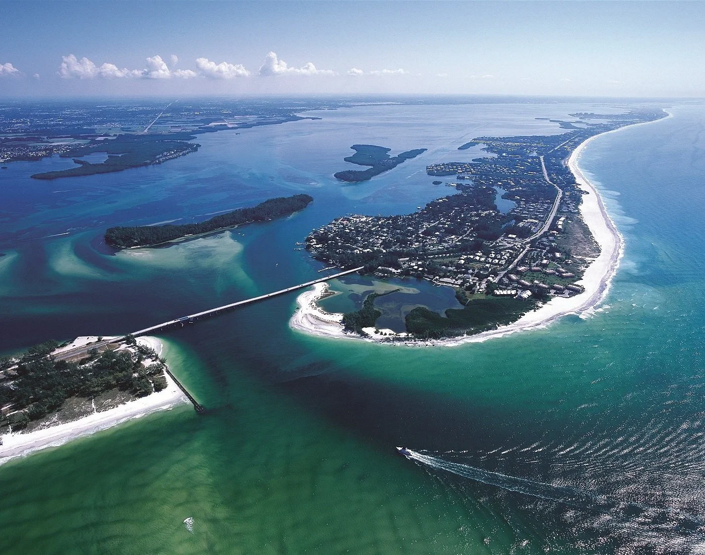 Sarasota Motor Club - Sports Car Rental Sarasota FL - Aerial view of a coastal area showing a peninsula, bridges, a river, and the Atlantic Ocean with waves.