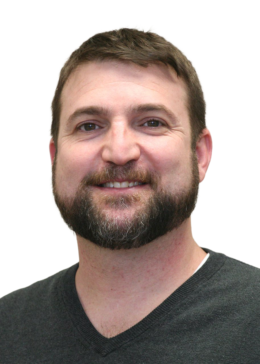 Close-up of a smiling man with short brown hair, a beard, and wearing a dark gray v-neck shirt.
