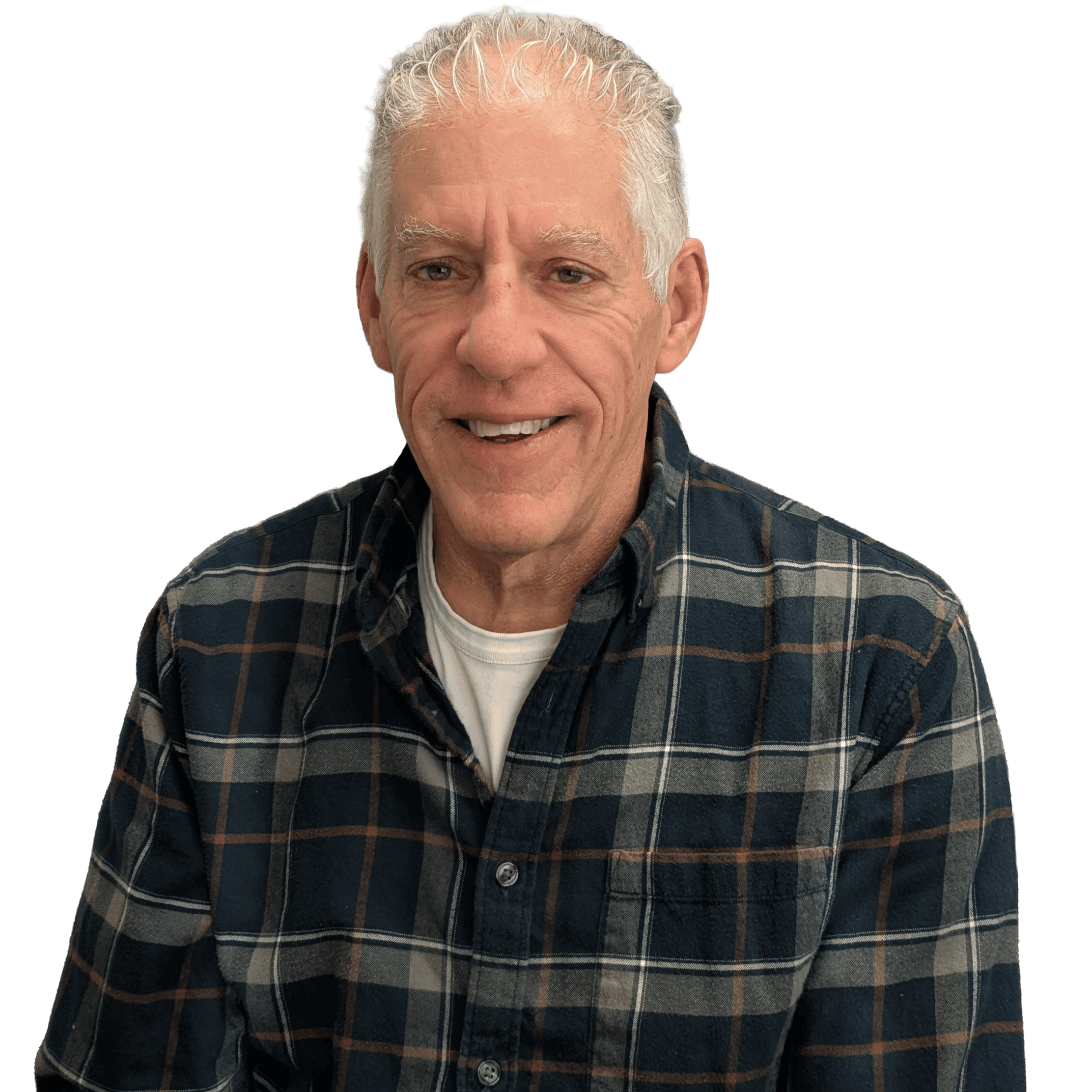 A middle-aged man with gray hair, wearing a dark plaid shirt over a white t-shirt, smiling and sitting against a black background.