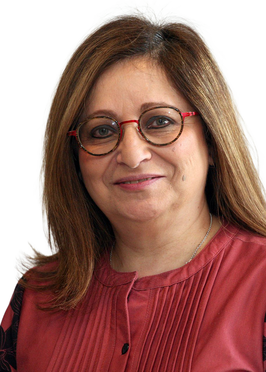 Kathy Laszlo with long brown hair, wearing round glasses with red and tortoiseshell frames, a pinkish-red blouse with pleats, and a silver necklace, smiling at the camera.