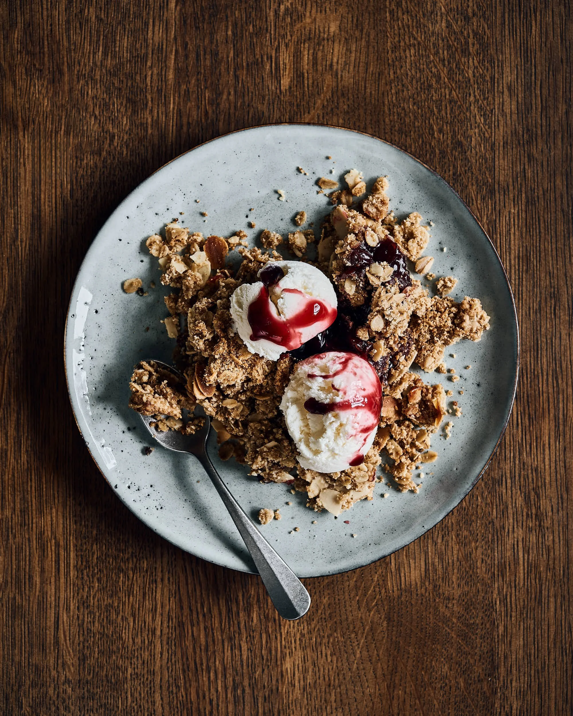 Rustikaalsel taldrikul serveeritud murelikrõbedik vaniljejäätise ja kirsisiirupiga