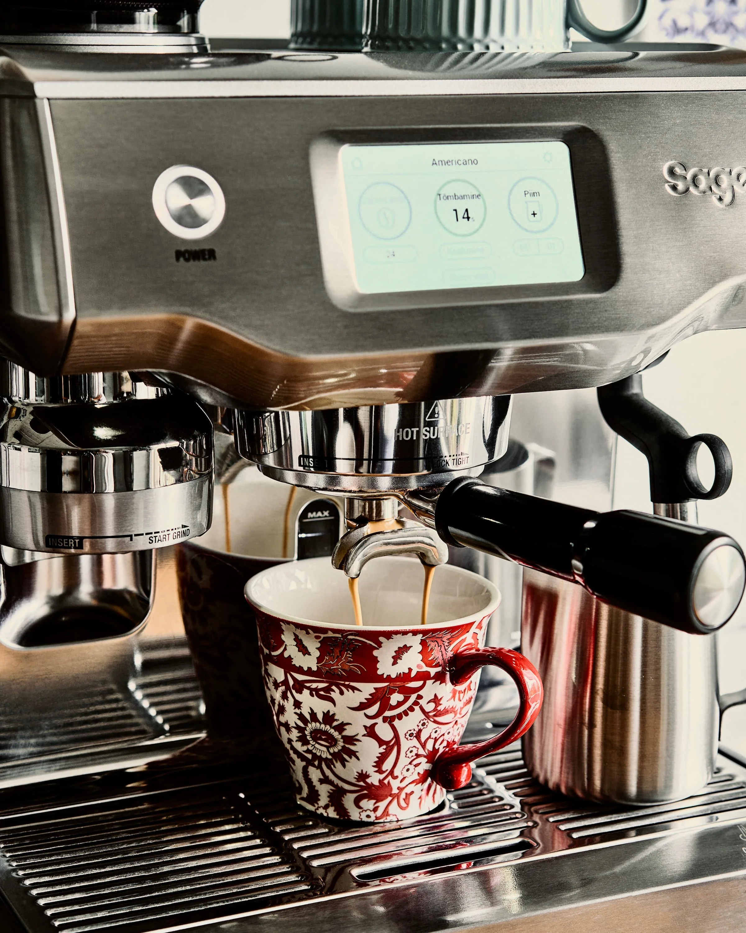 Espressomasin töös - kuldne espresso voolamas punasesse kruusi