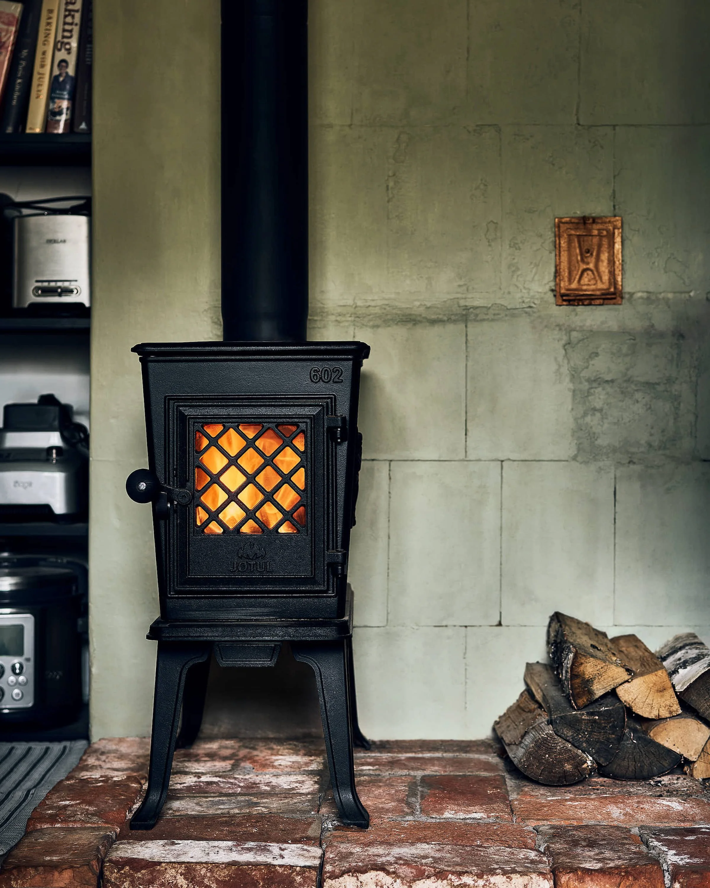 Must malmahi, millesse on tuli tehtud. Küttepuud ja rohekas soemüür punastest tellistest alusel