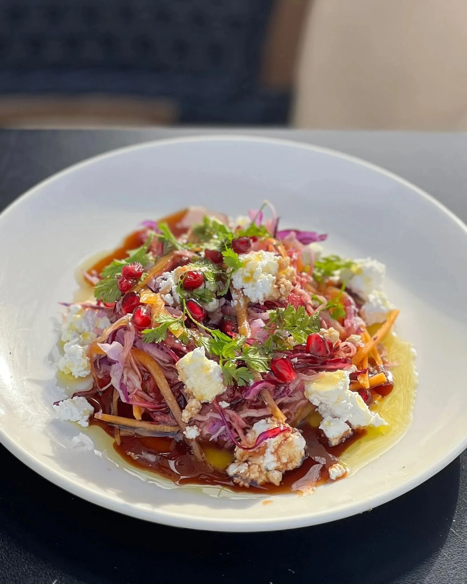 Salade colorée avec des légumes, fromage et grenade dans une assiette blanche.