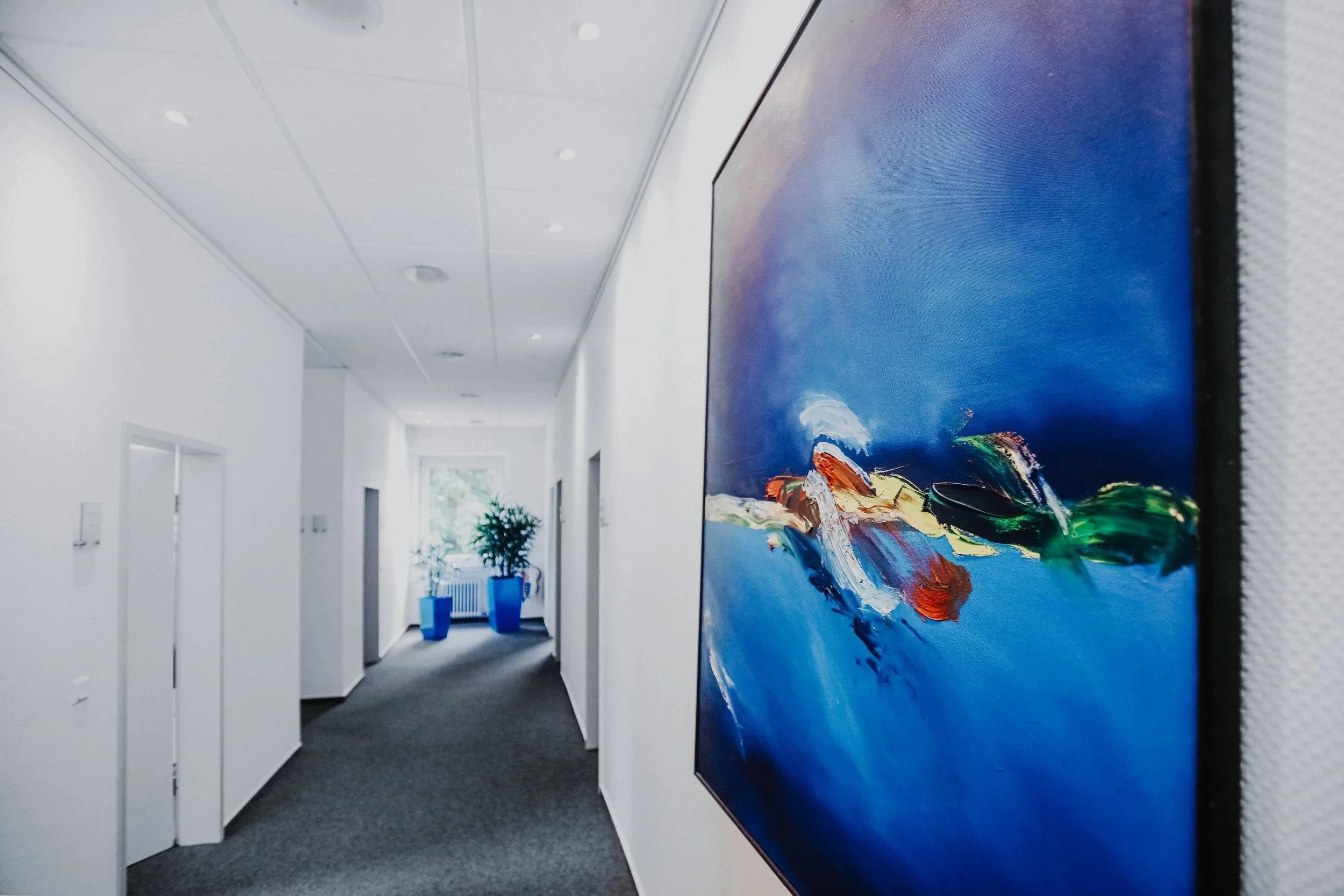 Heller Flur der Kanzlei mit Kunstgemälden an den Wänden