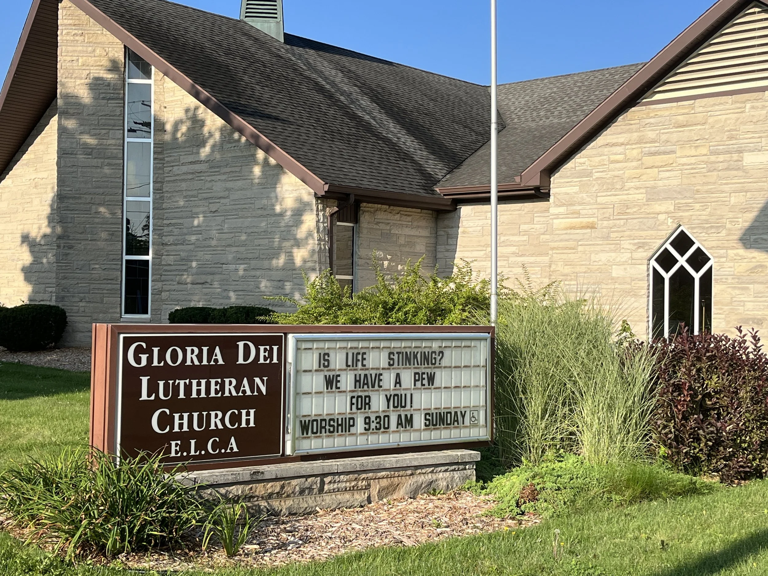 Sign outside Gloria Dei Lutheran Church with message board that reads: "Is life stinking? We have a pew for you! Worship 9:30 AM Sunday."