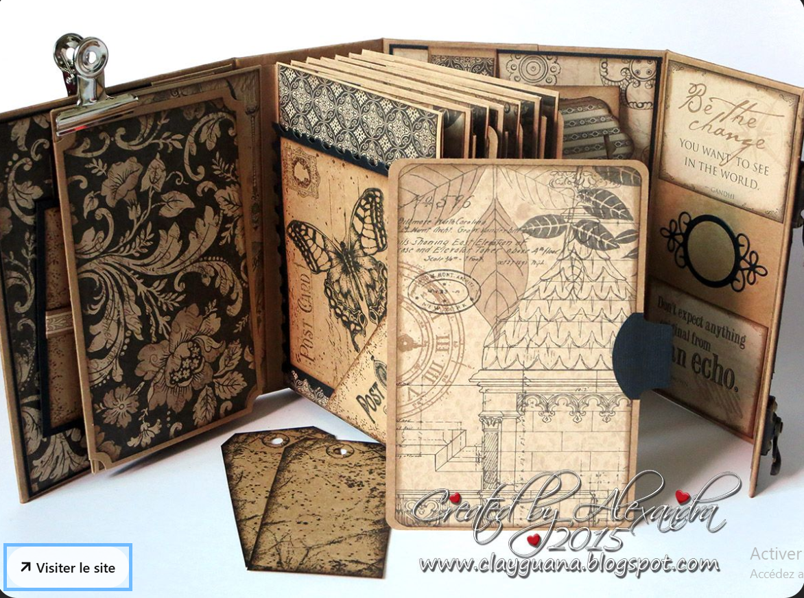 Un album de scrapbooking décoré avec des motifs vintage, notamment des papillons, des motifs floraux, des citations inspirantes et des dessins d'architecture, avec deux petites cartes et une pince argentée.