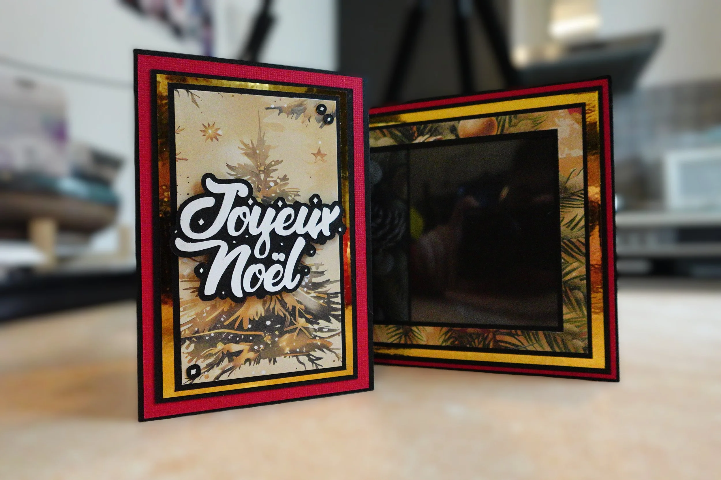 Carte de Noël avec le message "Joyeux Noël" sur un fond festif rouge et doré avec des décorations de saison.