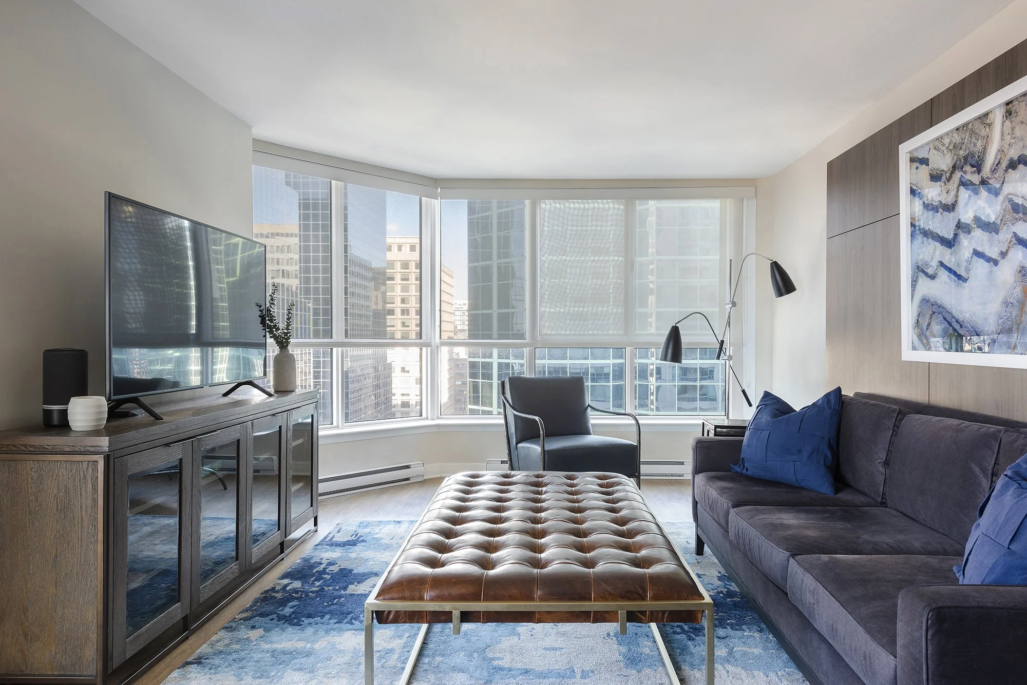 Family room makeover in Ottawa featuring a tufted wool area rug and a cognac leather ottoman. 