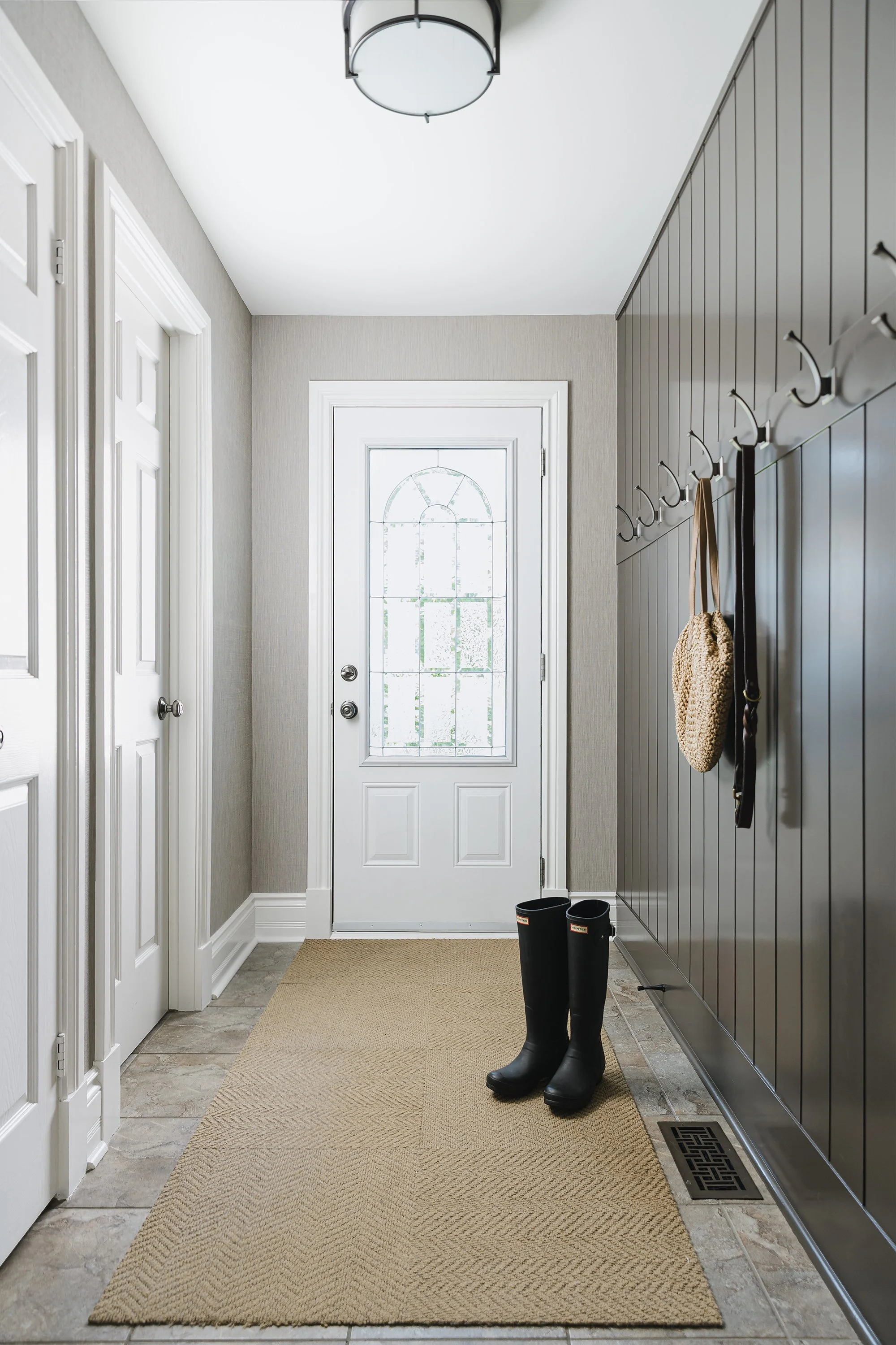 Mudroom design for an Ottawa family home featuring custom wall paneling and durable textured wallpaper. 