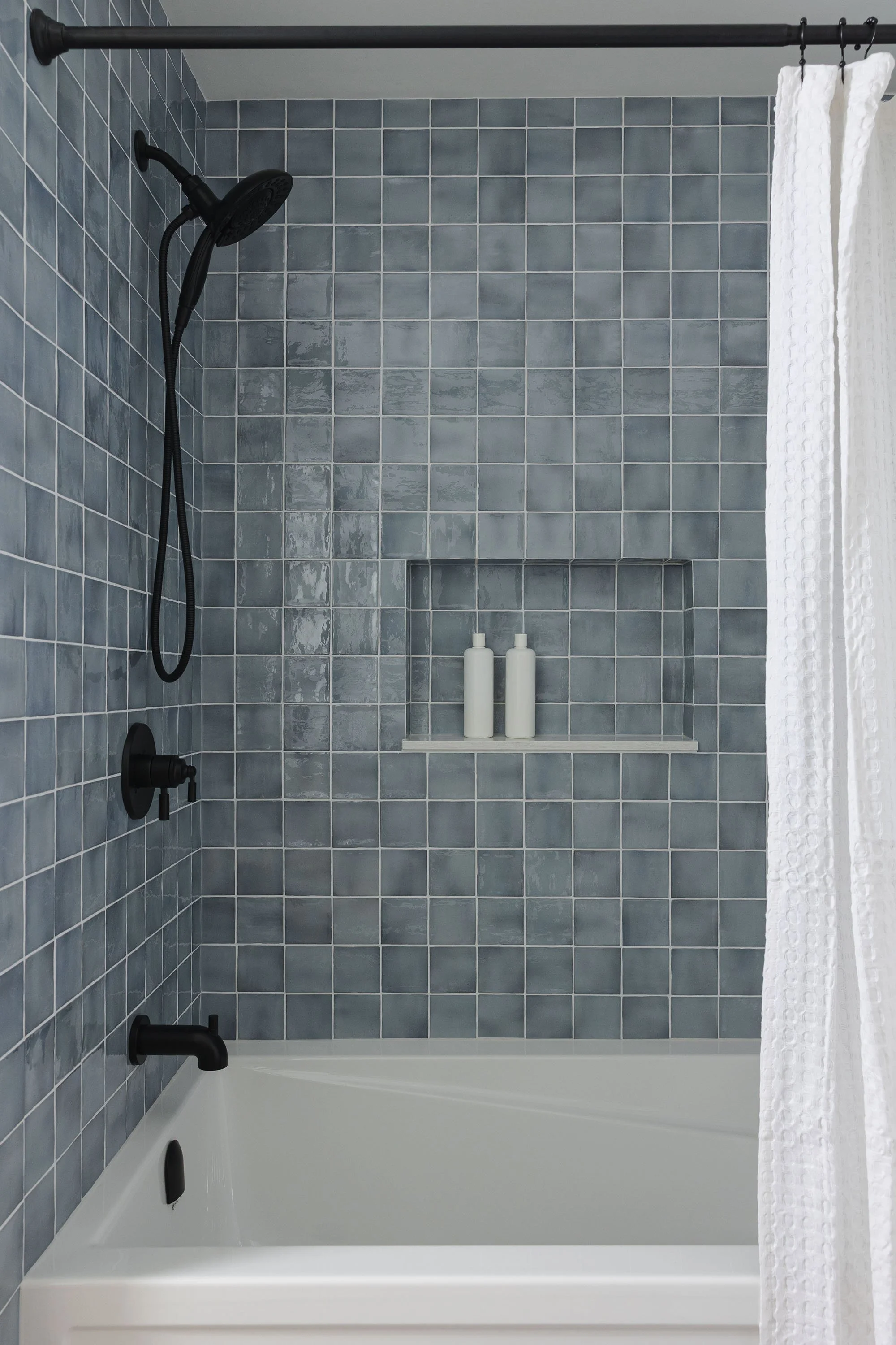 Bathroom renovation in Ottawa featuring a blue shower tile with black accents. 