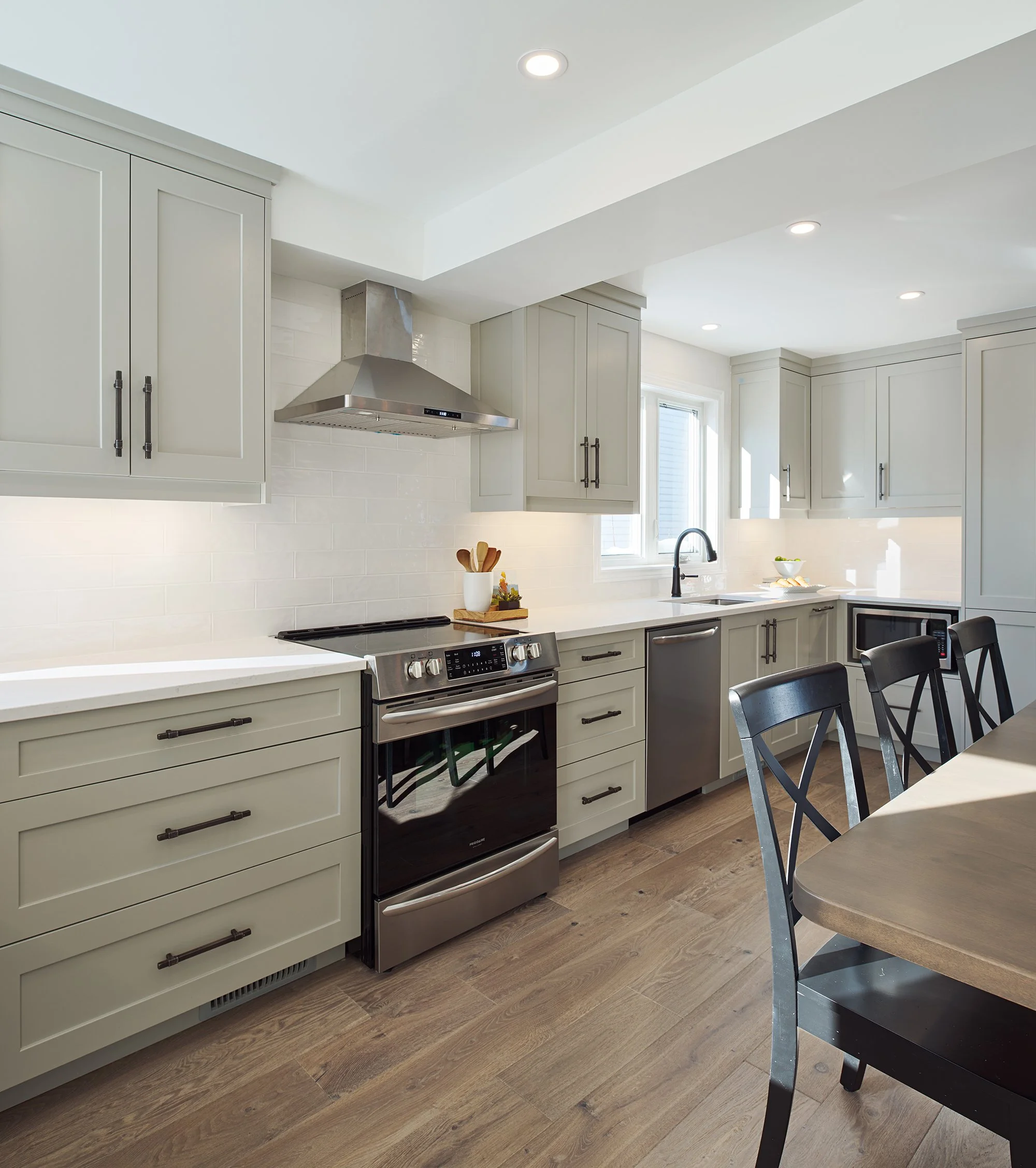 Custom kitchen renovation in Ottawa featuring warm grey shaker cabinets and an exposed hood fan.