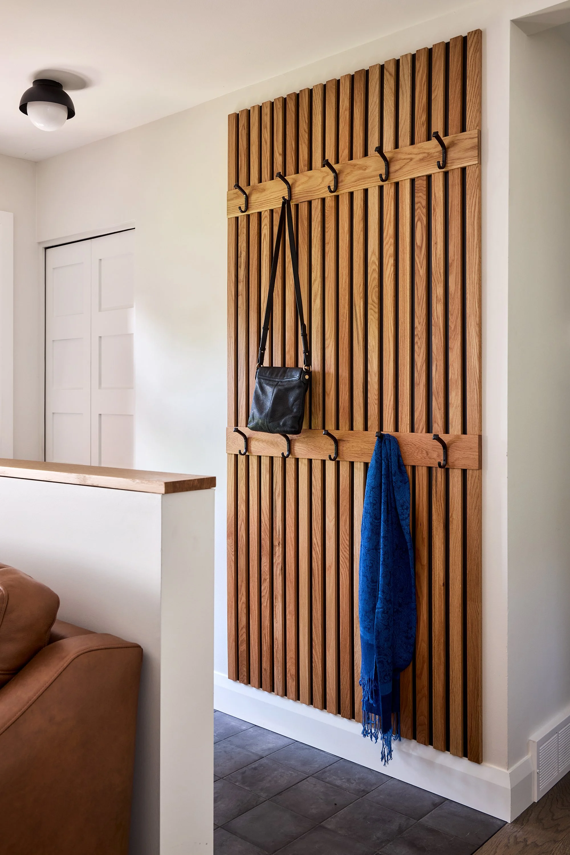 Open concept home design for an Ottawa family home featuring a white oak slat accent wall with hooks.
