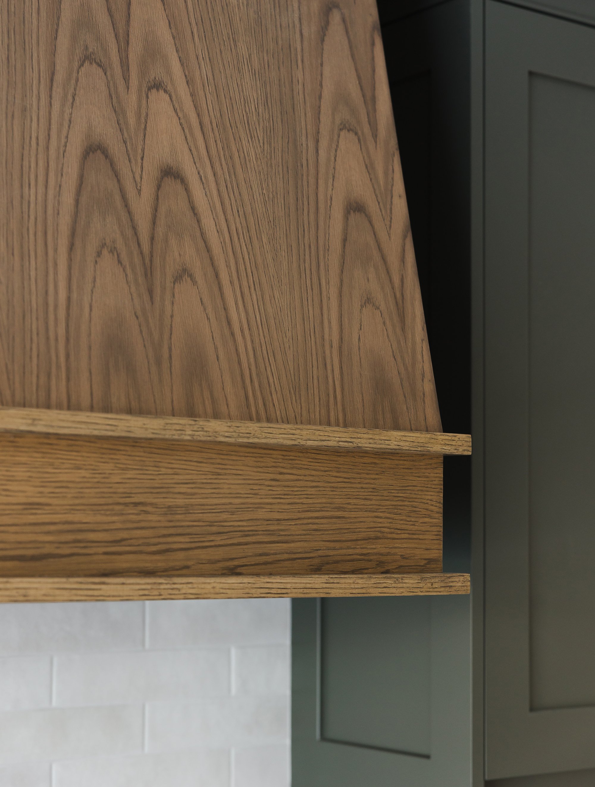 Custom kitchen renovation in Ottawa featuring green shaker cabinets and a custom oak hood fan. 