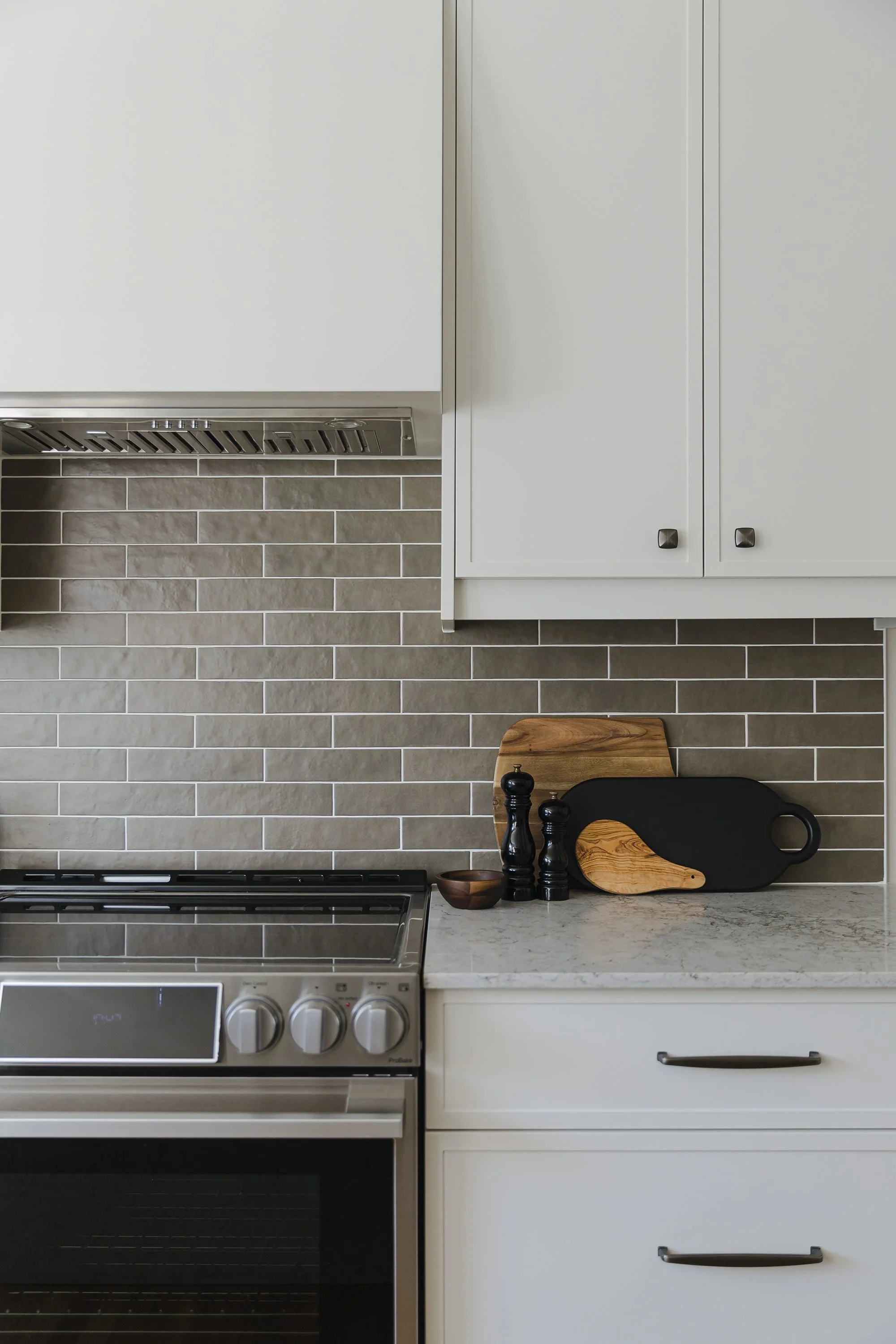 Custom kitchen design for an Ottawa family home featuring light coloured skinny shaker cabinets and a custom hood fan. 