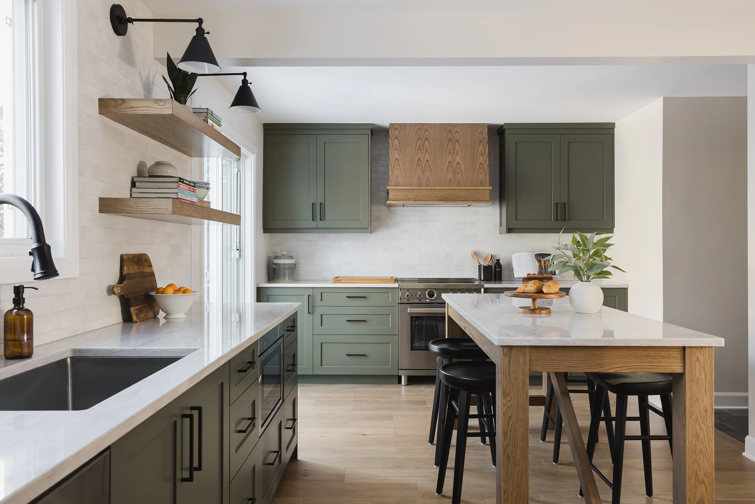 Custom kitchen design in Ottawa featuring green shaker cabinets and a decorative oak hood fan. 