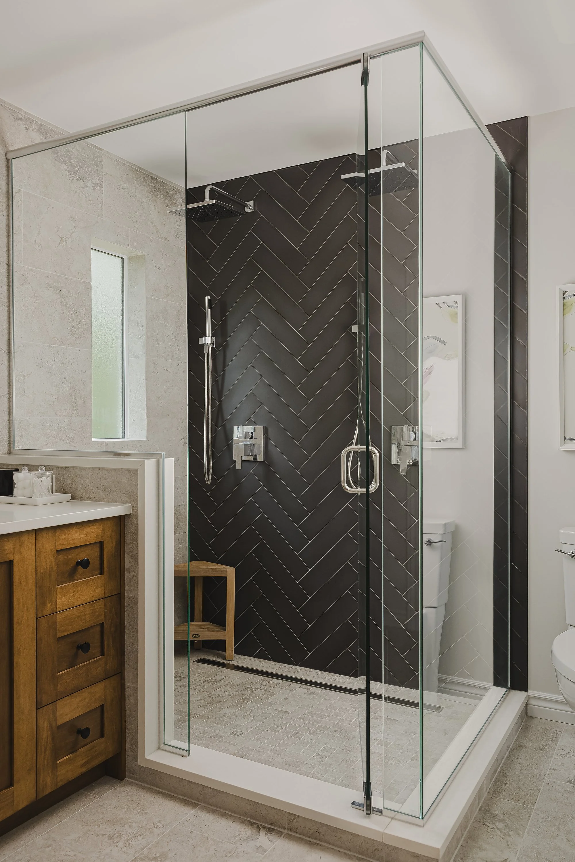 Ensuite renovation in Ottawa featuring a custom glass shower with charcoal herringbone tile and a teak bench.