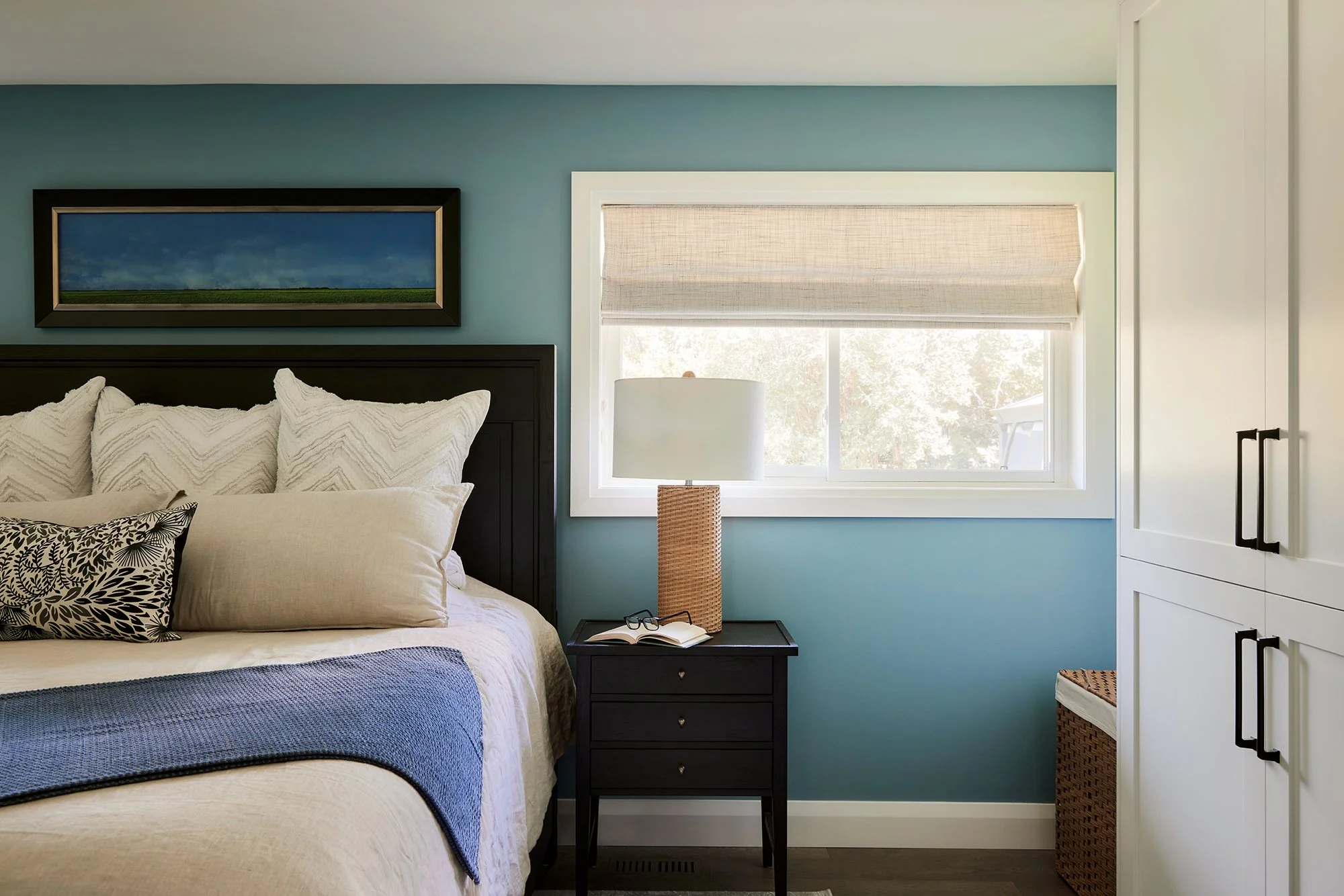 Principal bedroom design for an Ottawa family home featuring a black stained wood bed frame and nightstands. 