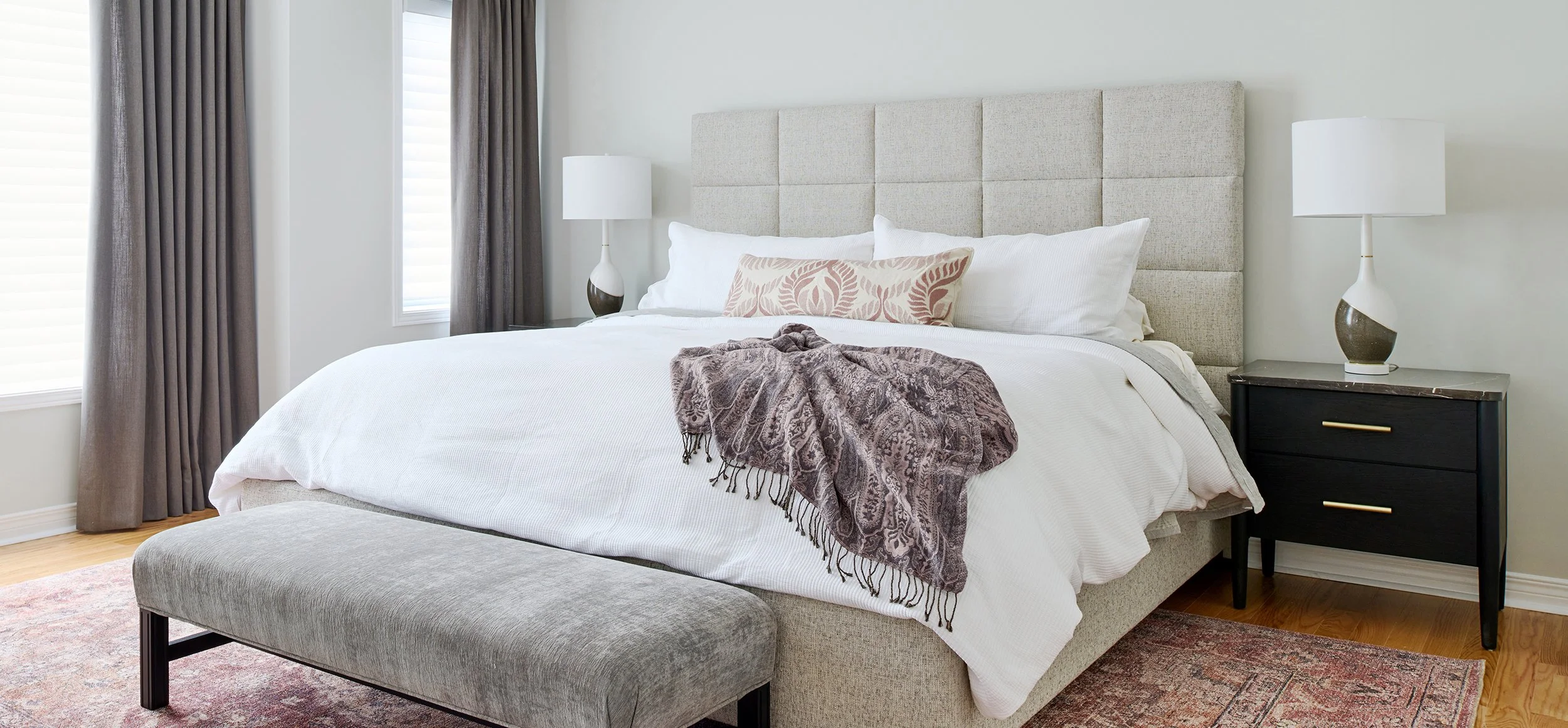 Principal bedroom design for an Ottawa family home featuring an upholstered bed frame and charcoal grey custom drapery.