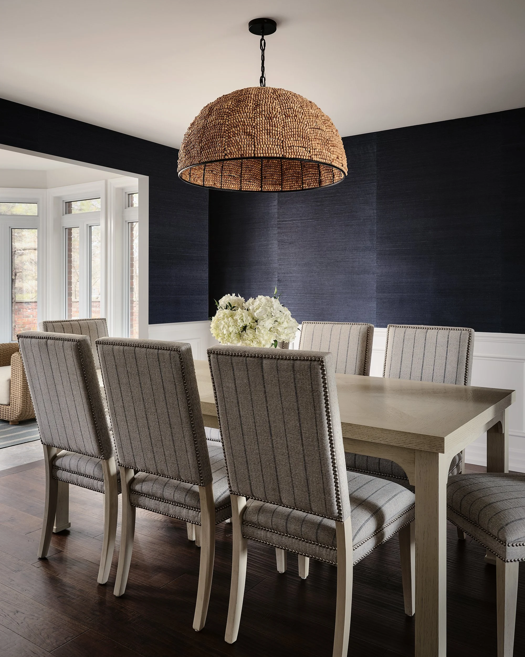 Natalie Cox, principal designer of CPI Interiors, is sitting in front of a woven chair. 