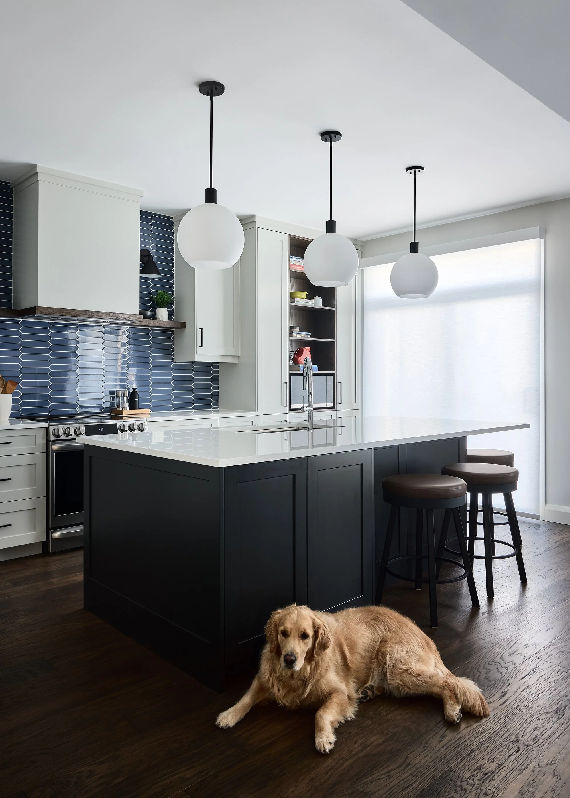 Custom kitchen renovation in Ottawa featuring light shaker cabinetry and three globe pendants over a large island. 