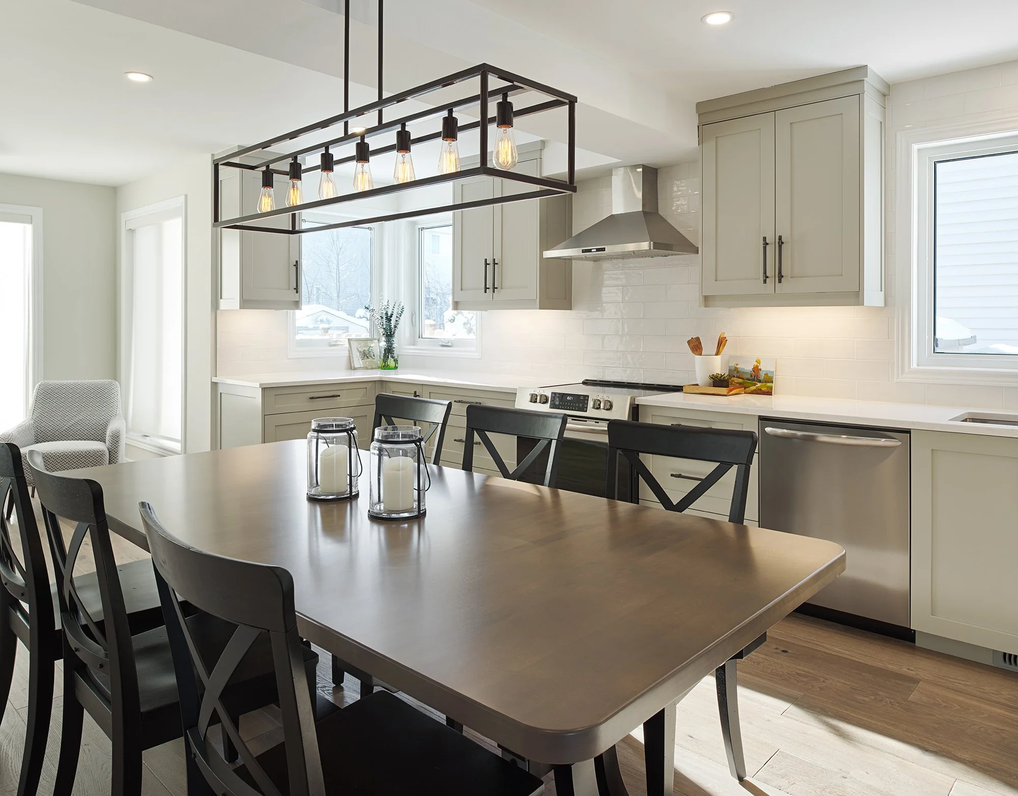 Custom kitchen renovation in Ottawa featuring warm grey shaker cabinets and a large farmhouse table with black chairs. 