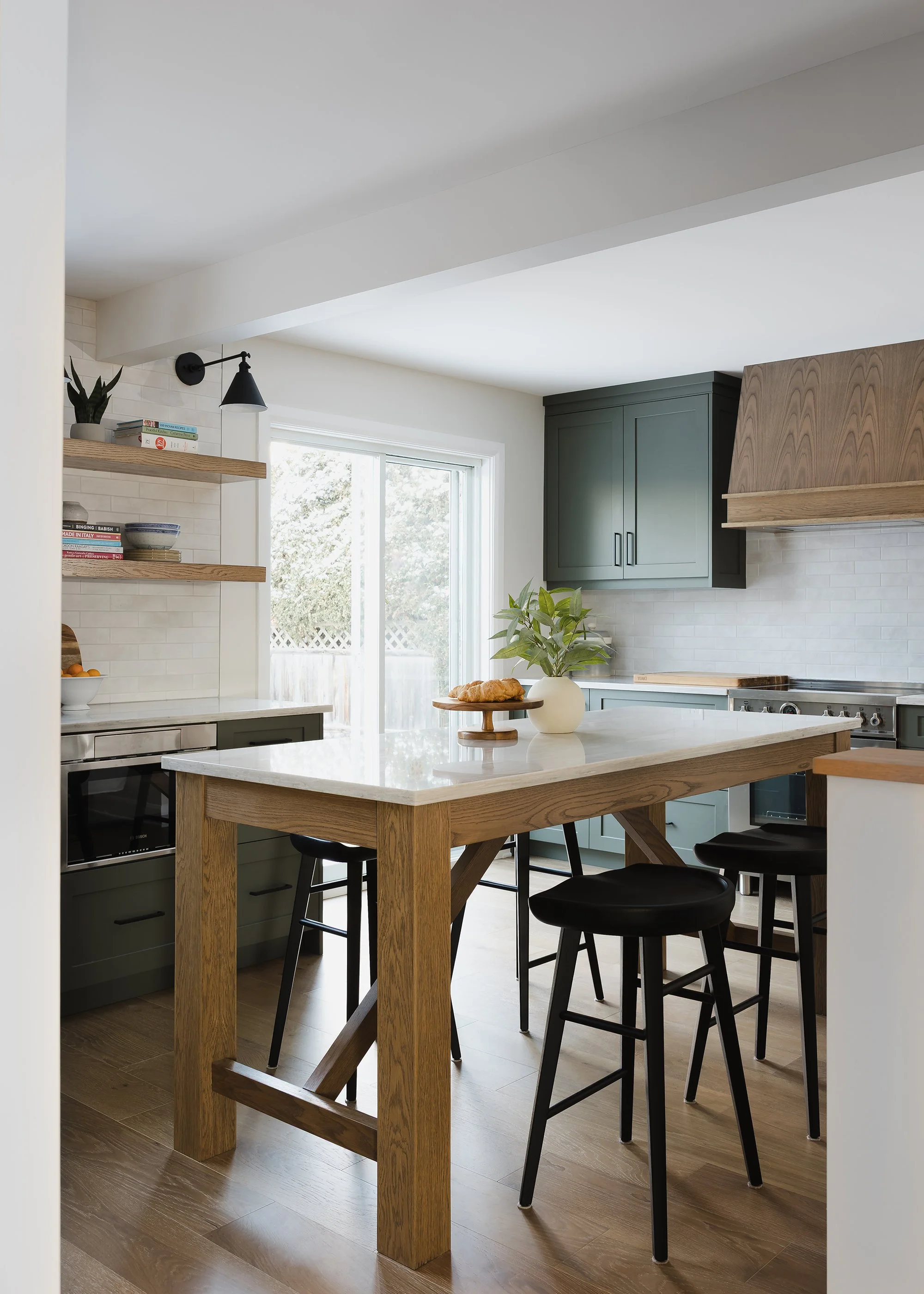 Custom kitchen renovation in Ottawa featuring green shaker cabinets and floating white oak shelves. 