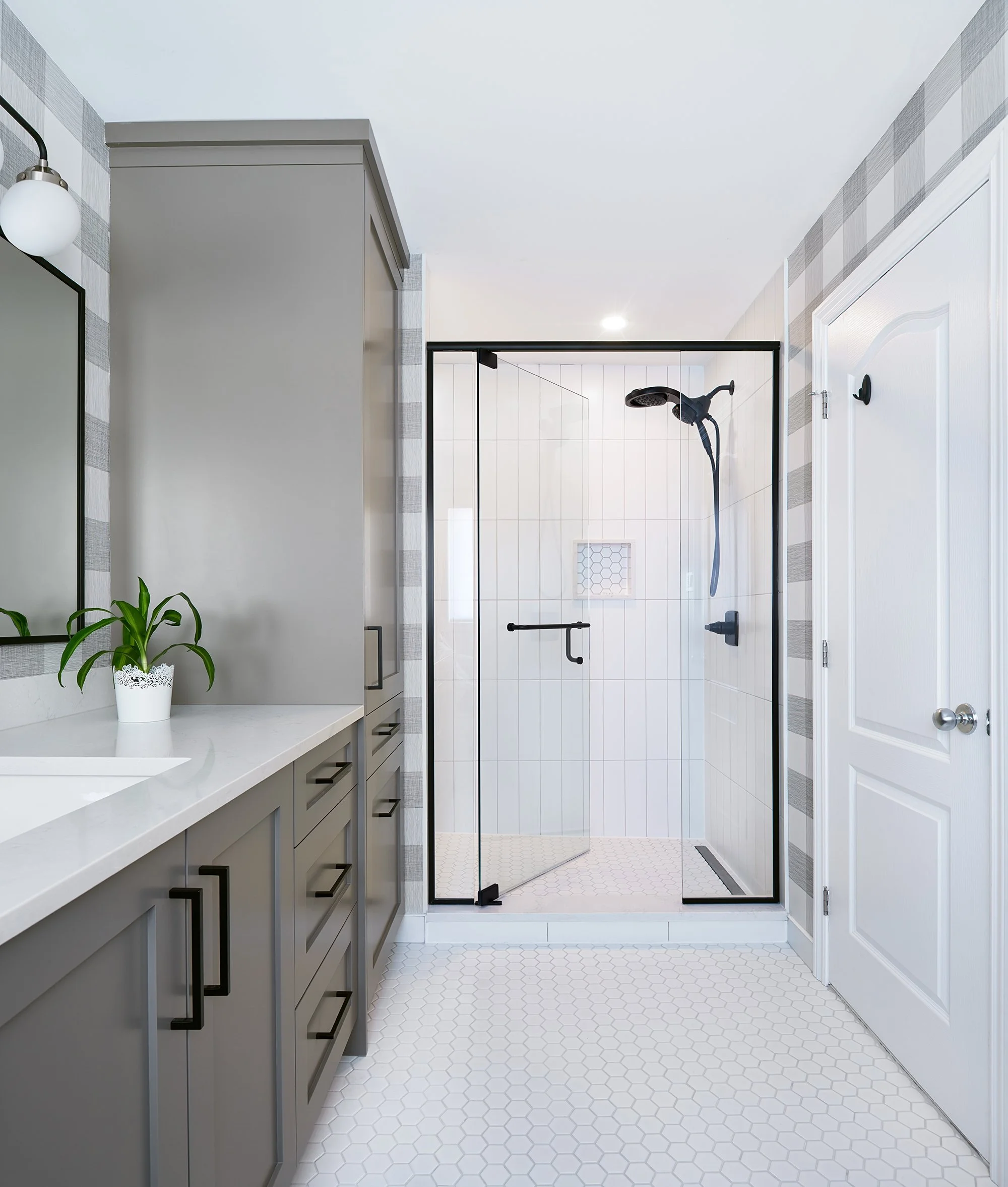 Ensuite bathroom renovation in Ottawa featuring custom grey vanity with a storage tower and a bright large custom shower.