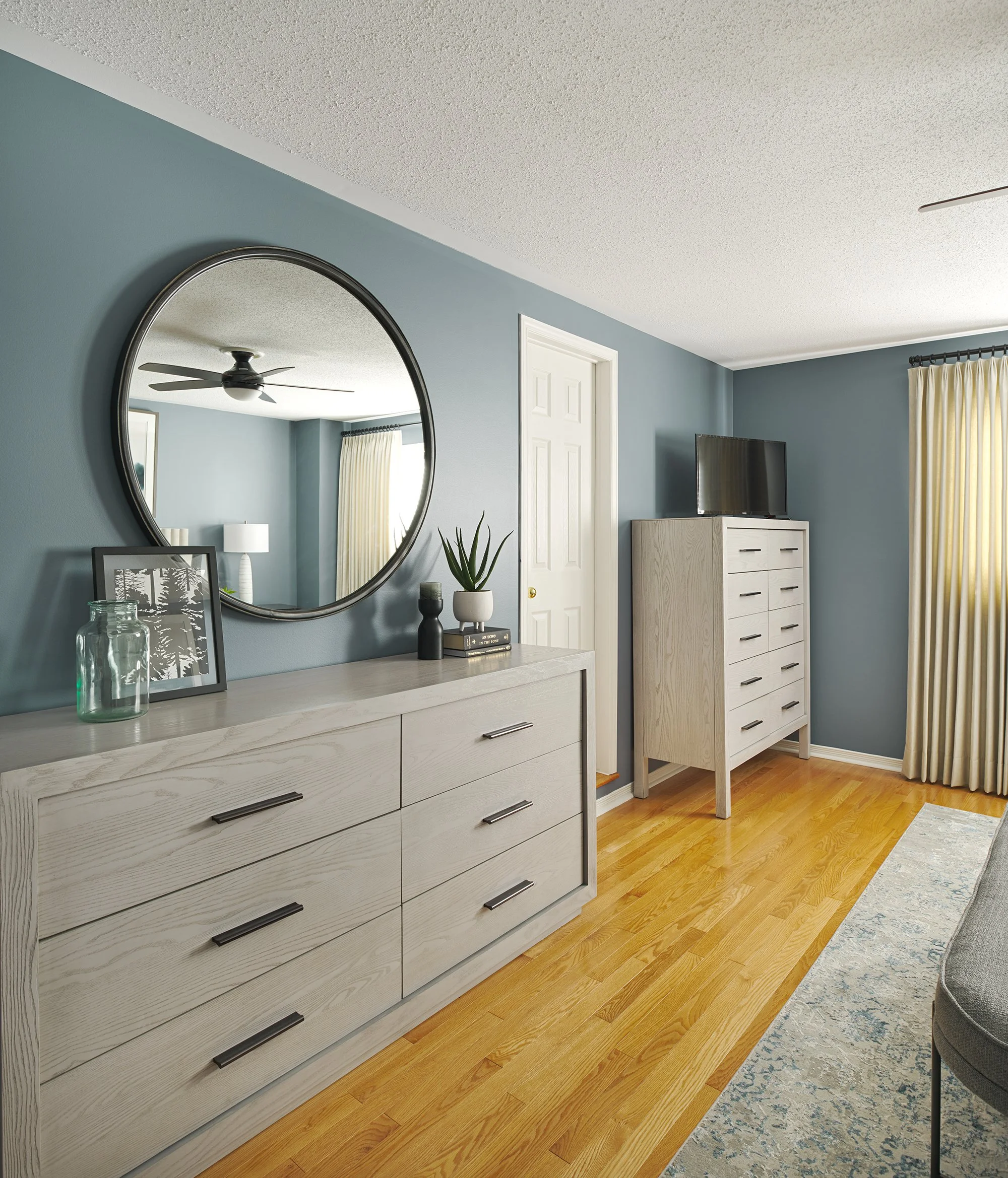 Principal bedroom design in Ottawa featuring grey modern dressers and a large mirror. 