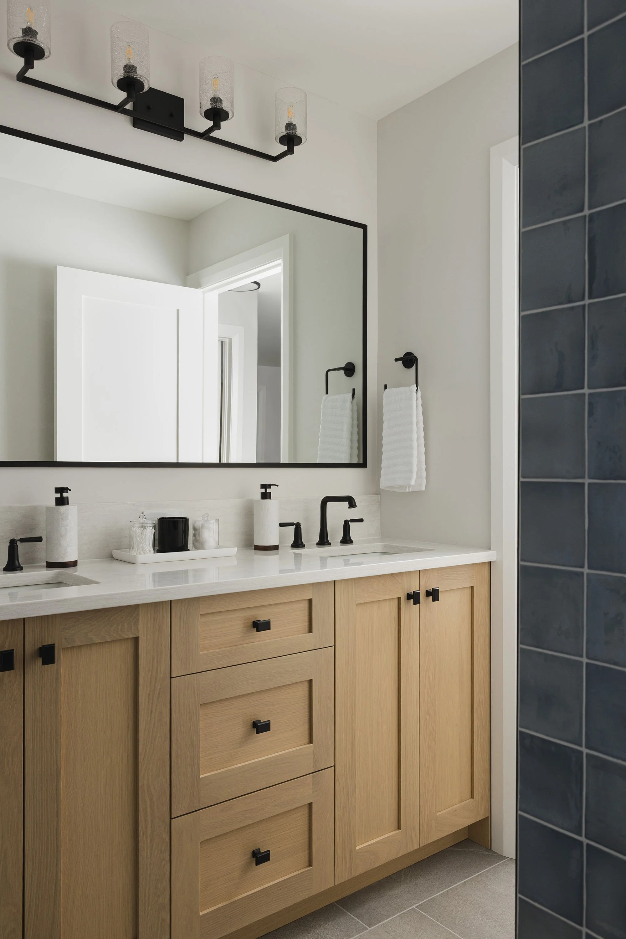 Bathroom renovation in Ottawa featuring a white oak vanity and blue shower tile. 