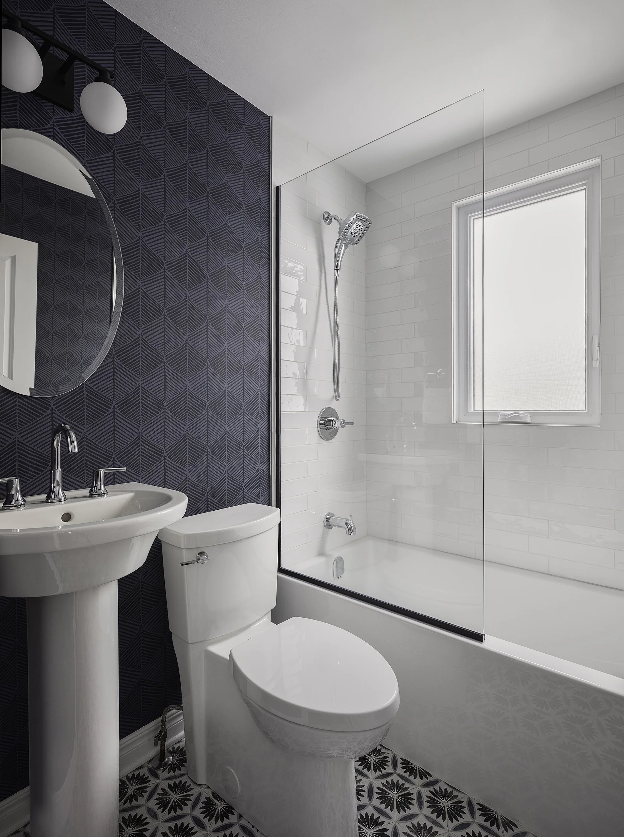 Main floor bathroom renovation in Ottawa featuring unique patterned floor tiles and deep blue wallpaper. 