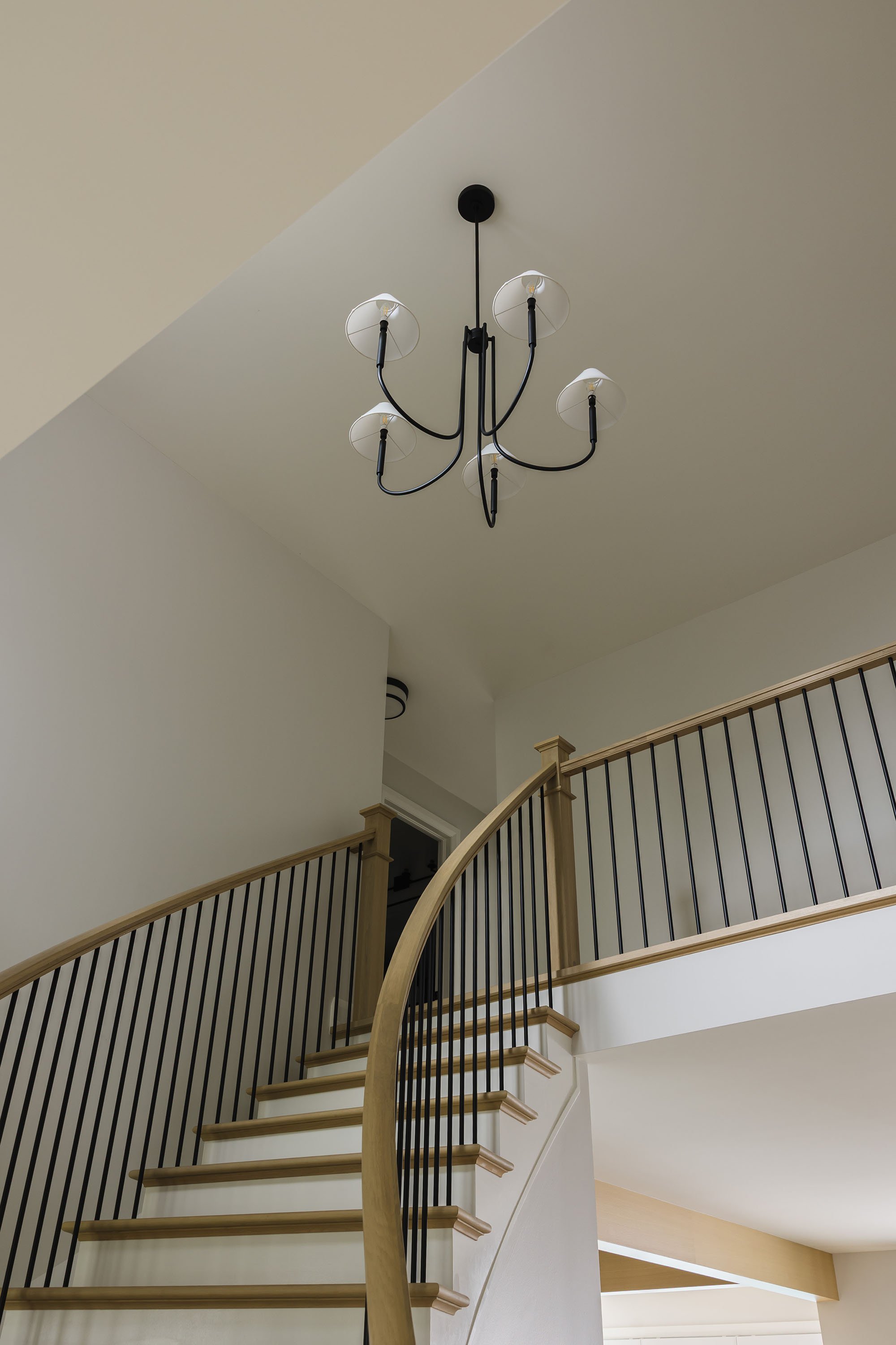 Renovation in Ottawa featuring a white oak staircase with black railings and a black chandelier. 