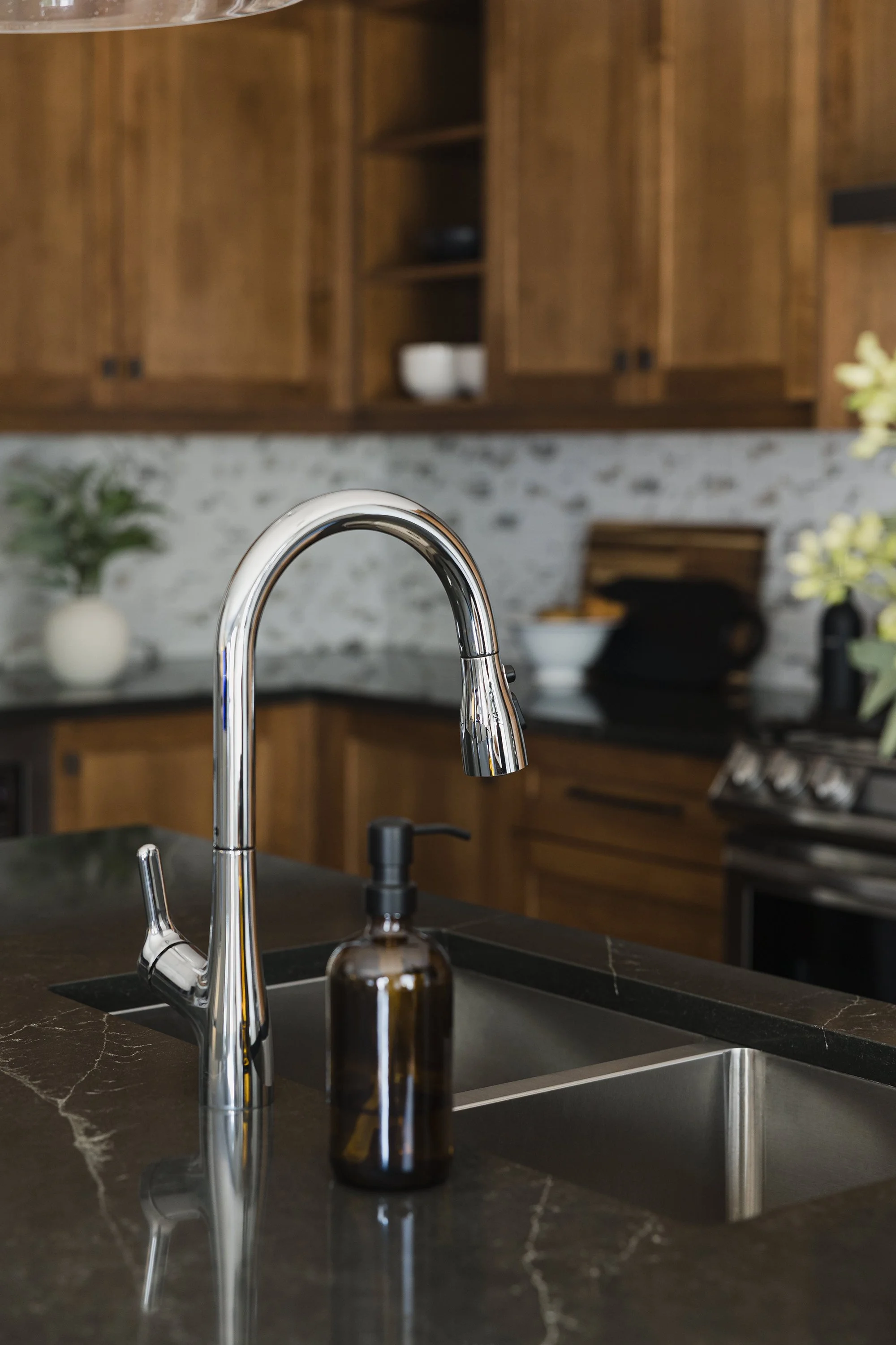 Custom kitchen renovation in Ottawa featuring warm maple cabinets and a chrome faucet with a sprayer and large sink on the island. 