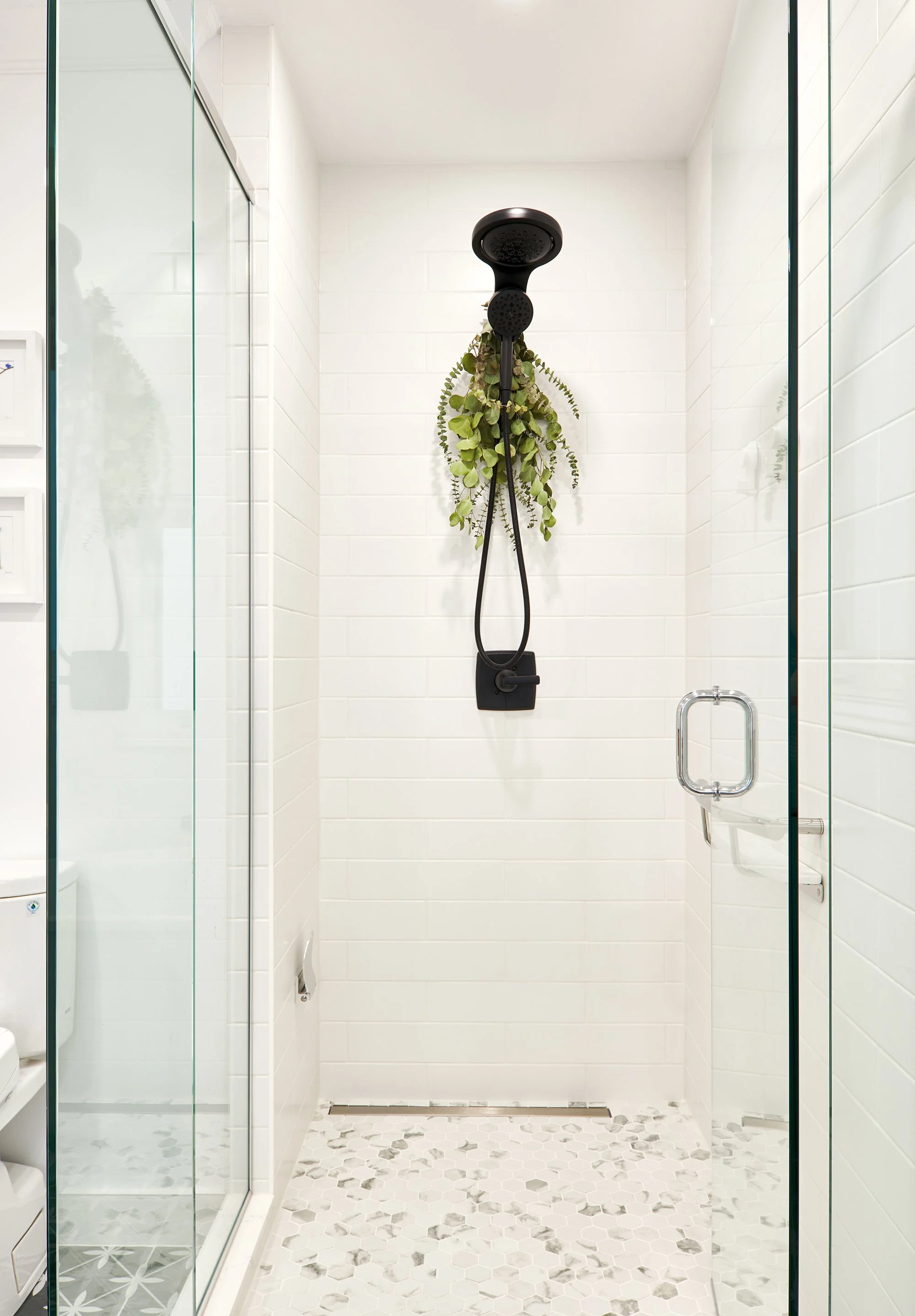 Ensuite bathroom design for an Ottawa family home featuring a bright shower with custom glass and black shower fixtures. 