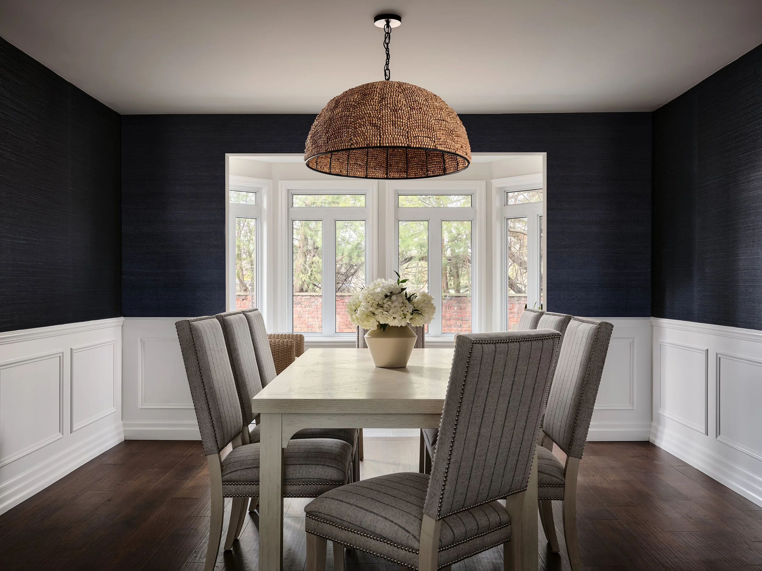 Dining room design for an Ottawa family home featuring navy grasscloth wallpaper and a woven chandelier.
