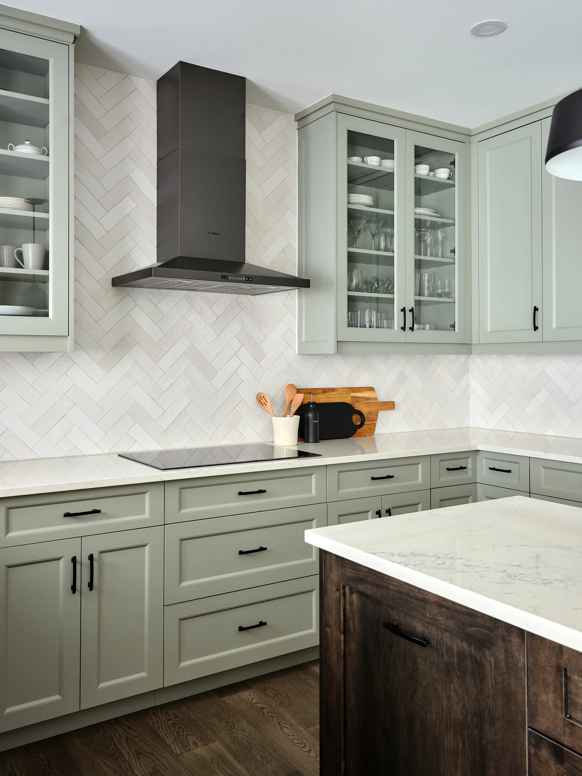 Custom kitchen renovation in Ottawa featuring warm green shaker cabinetry an exposed hood fan. 