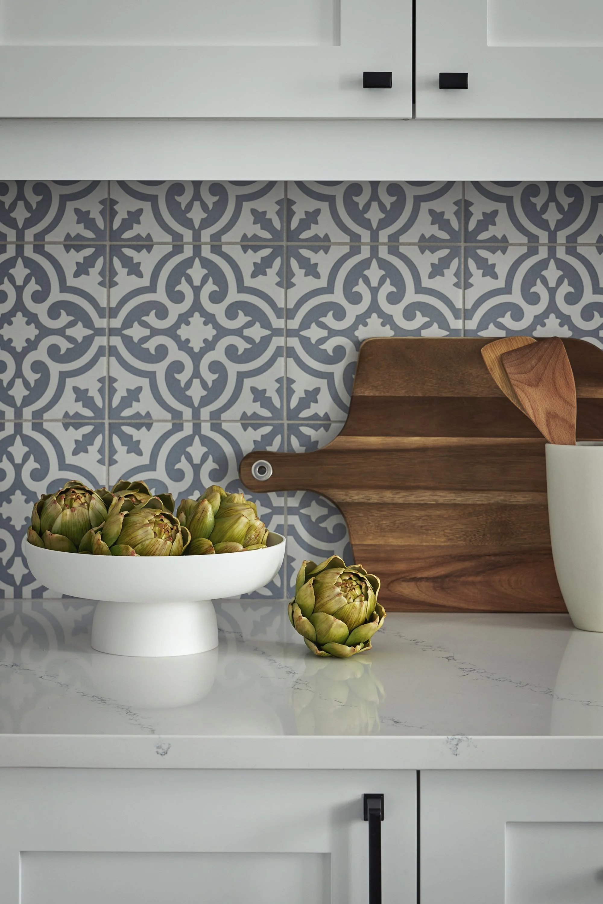 Custom kitchen renovation in Ottawa featuring white cabinets, black hardware and a patterned back splash. 