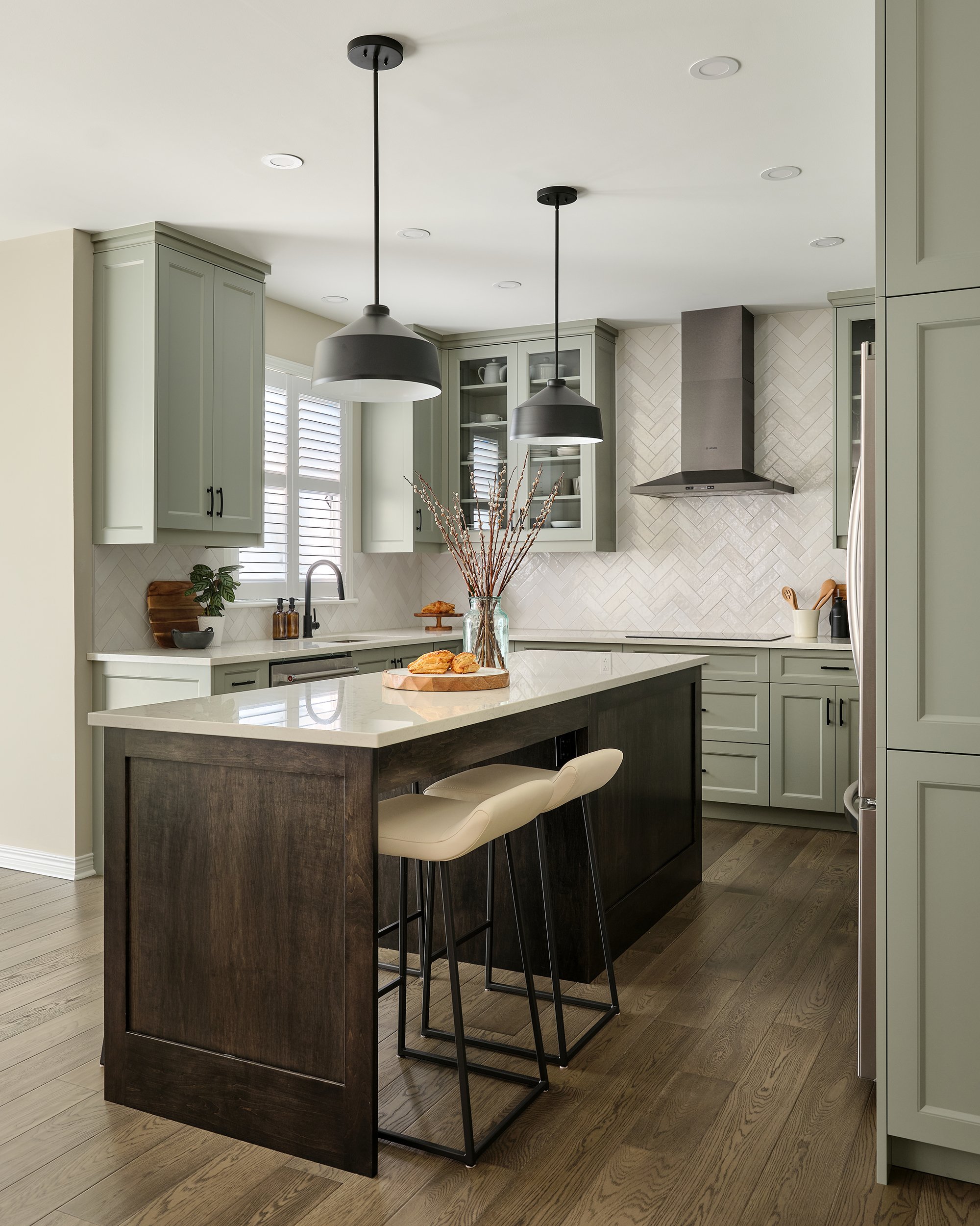 Custom kitchen renovation in Ottawa featuring warm green shaker cabinetry and a dark stained maple island with seating.