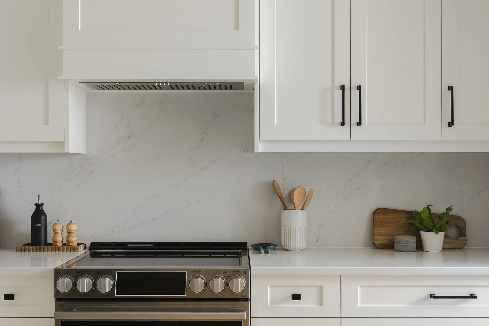 Kitchen renovation in Ottawa featuring white oak flooring and white shaker cabinets and a quartz backsplash.