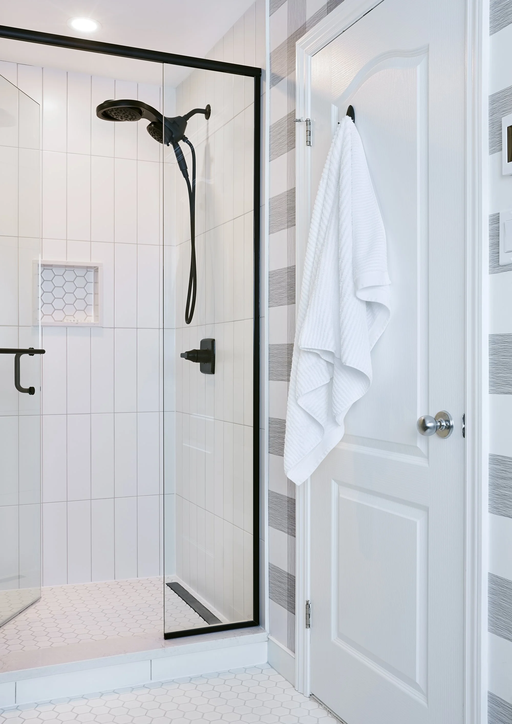 Ensuite bathroom renovation in Ottawa featuring a bright custom shower with bright white tile and black plumbing fixtures. 