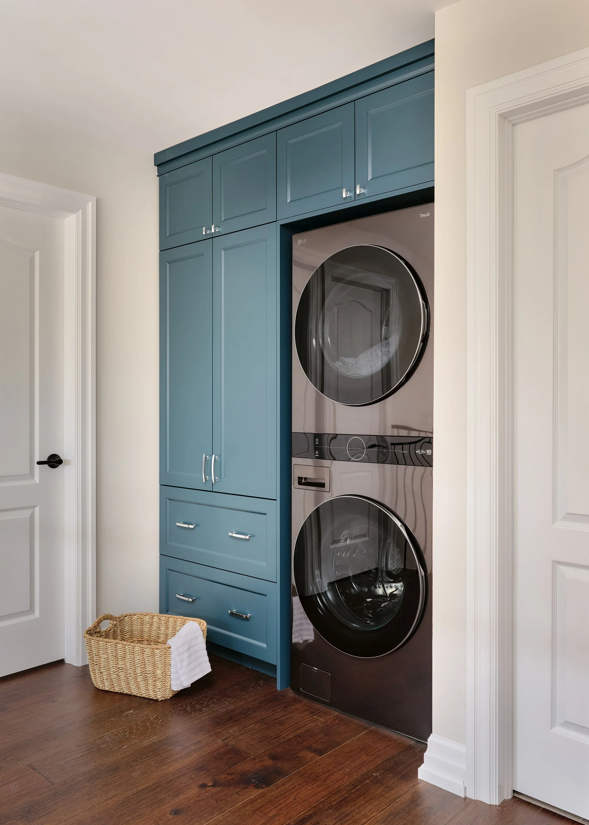 Laundry room design for an Ottawa family home featuring blue custom cabinets for ample storage.
