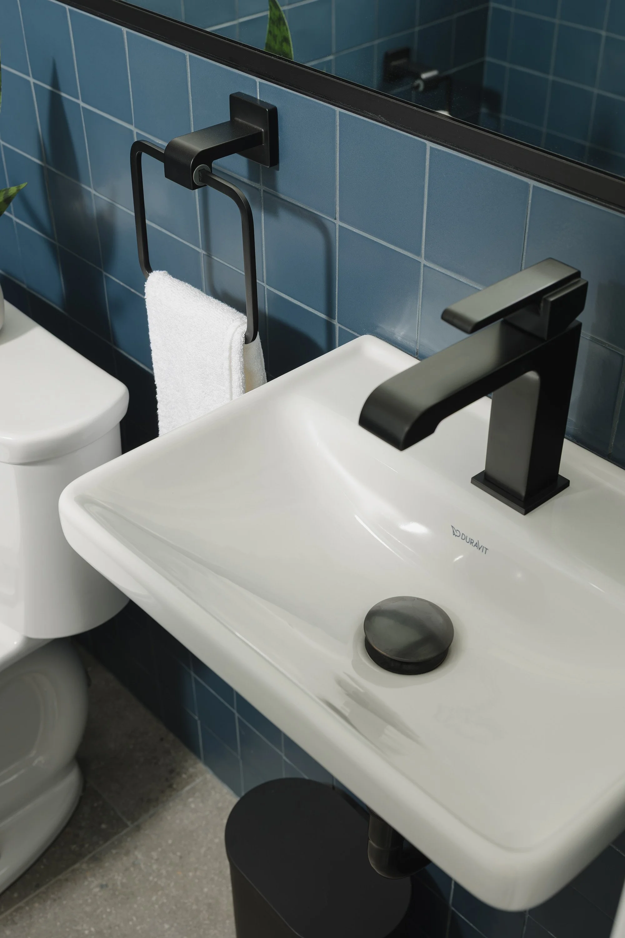 Ottawa interior design featuring a mid-century inspired powder room with blue wall tile and a small sink.  