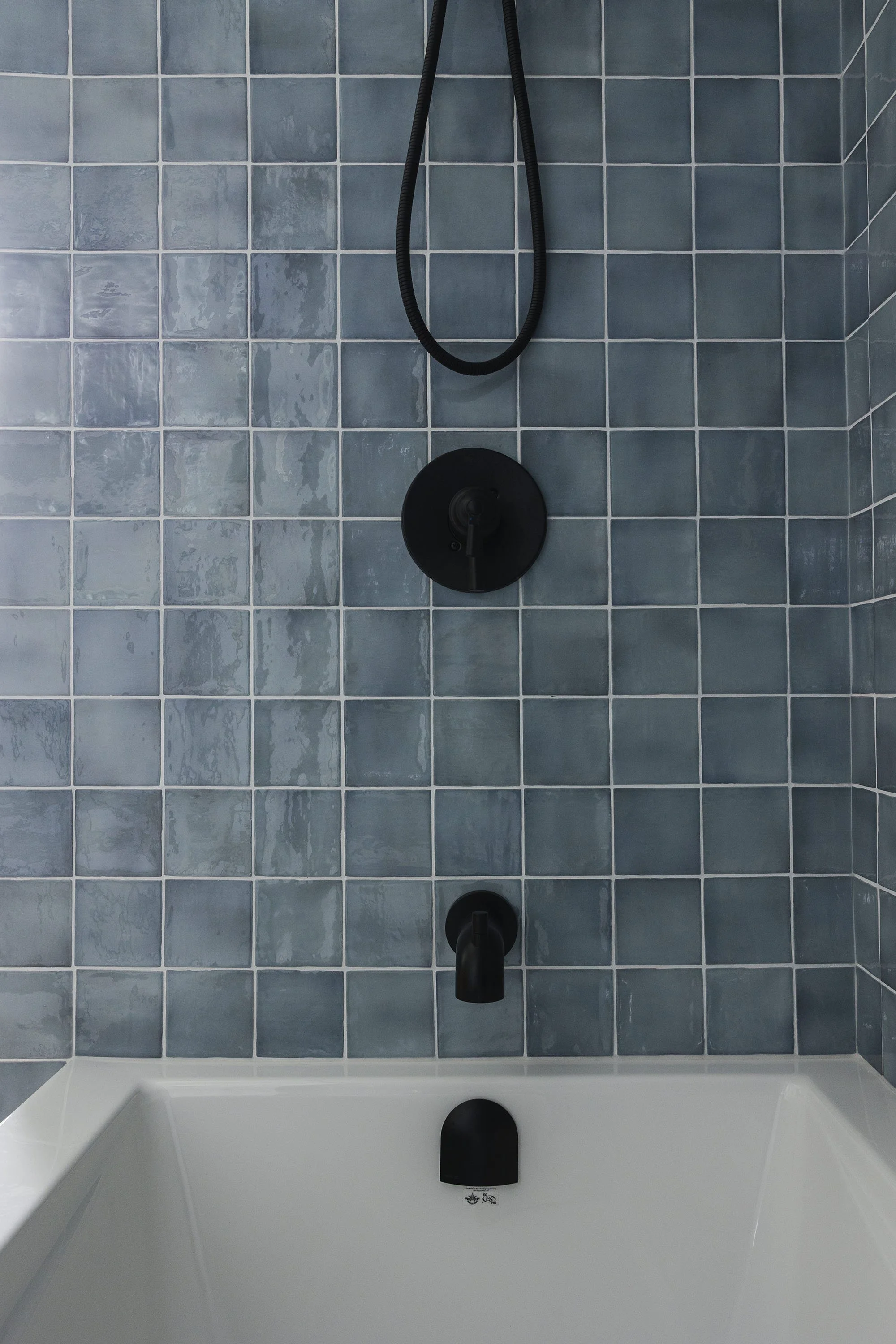 Bathroom renovation in Ottawa featuring blue tile in the shower with black accents.
