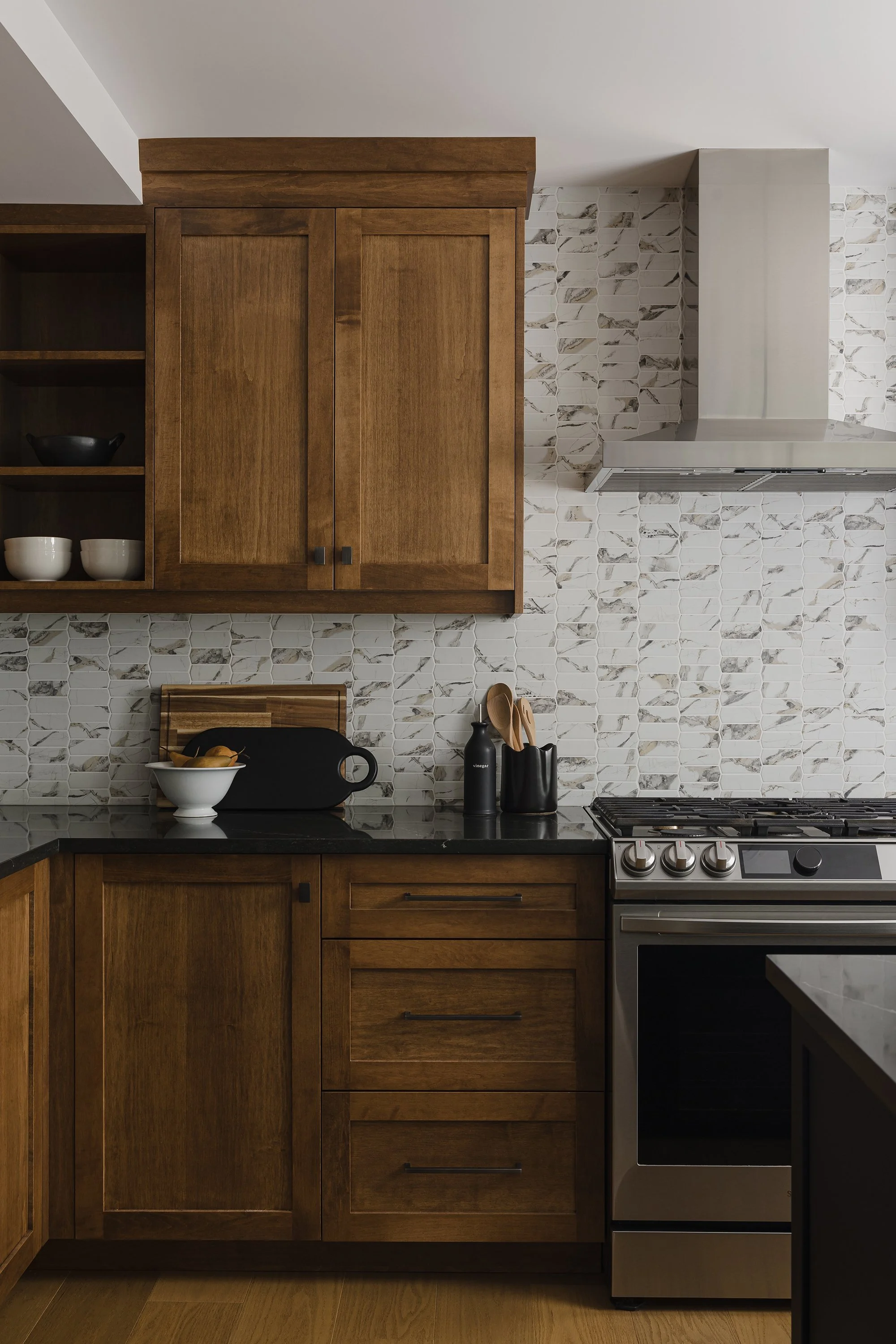 Custom kitchen renovation in Ottawa featuring warm maple cabinets and open shelves for cookbooks and a recycled glass backsplash. 