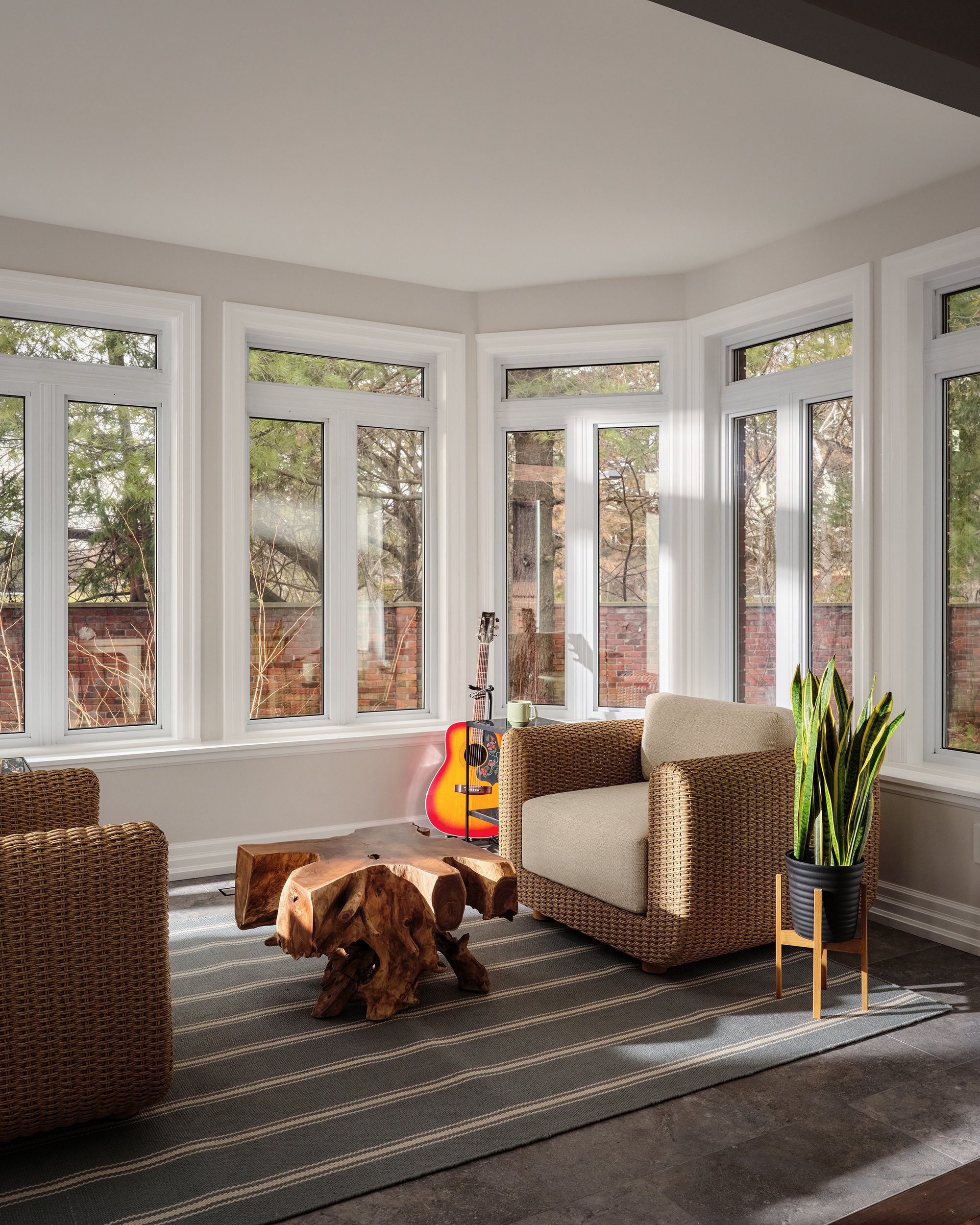 Sunroom design for an Ottawa family home featuring woven armchairs and a teak table.